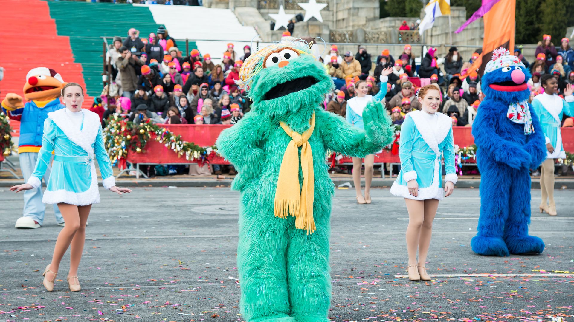 Photo of Rosita from Sesame Street, a green furry character, dancing in a parade