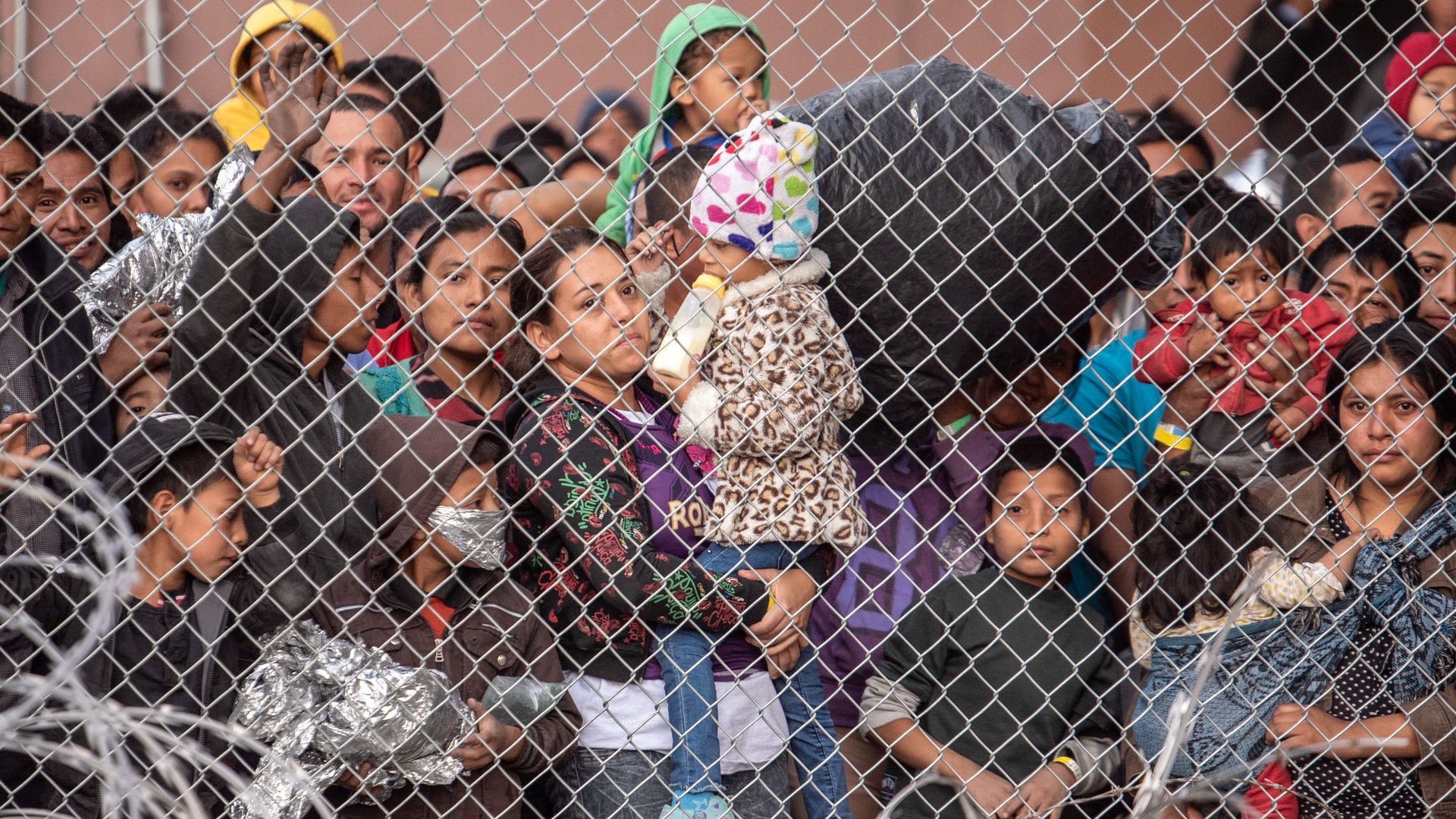Migrants are gathered inside the fence of a makeshift detention center in El Paso, Texas.
