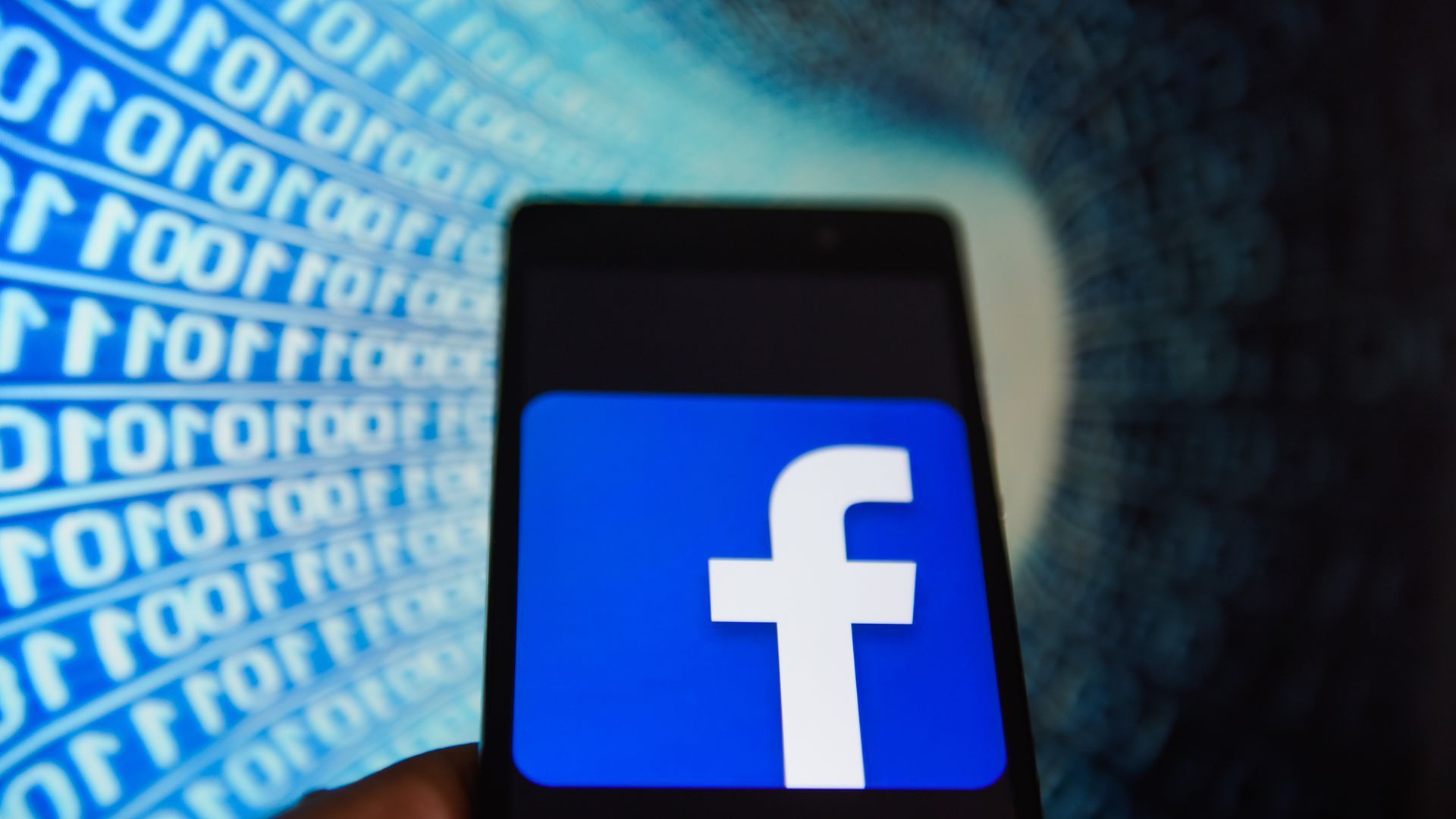The Facebook logo on a phone against a backdrop of ones and zeroes