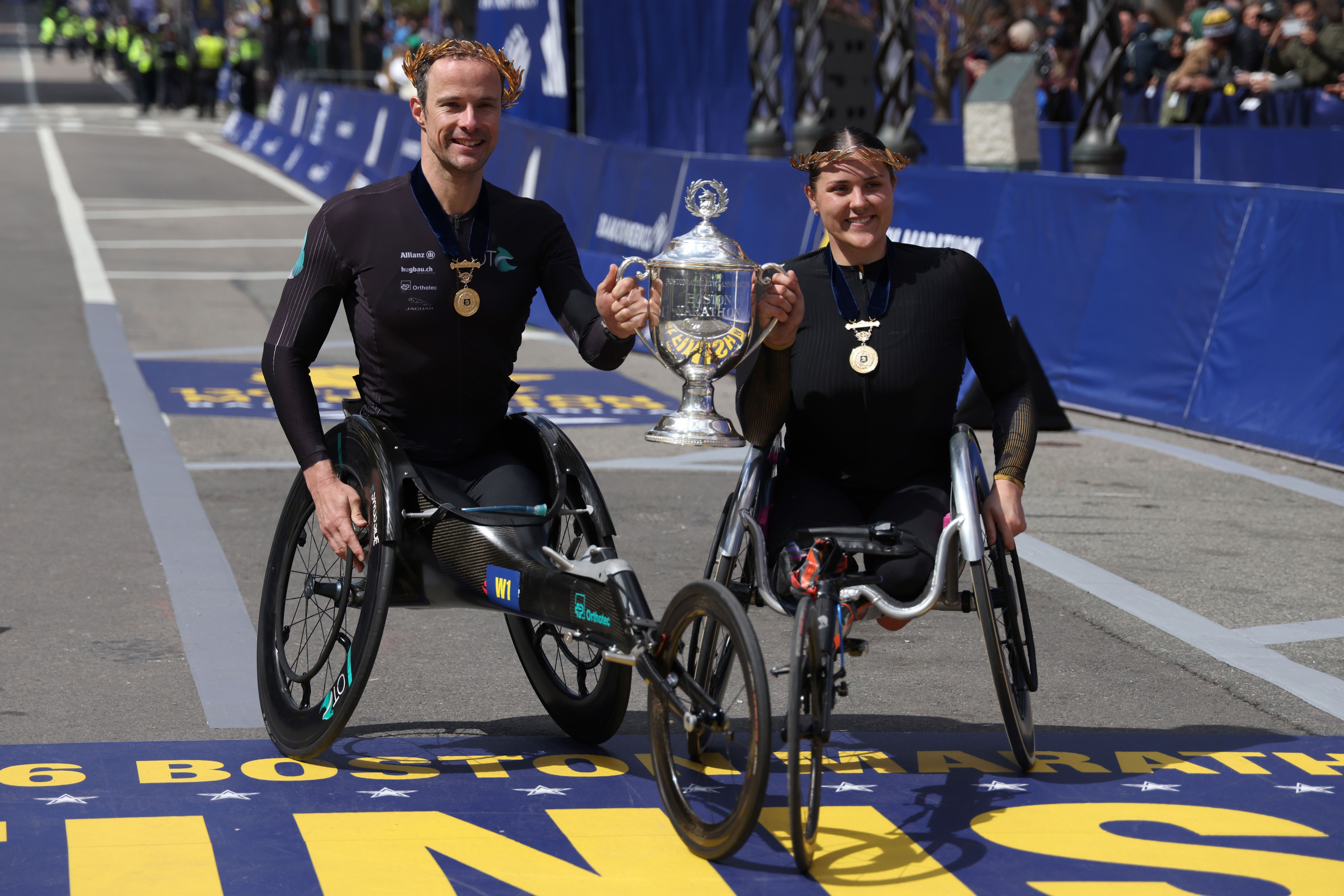 Marcel Hug and Eden Rainbow-Cooper of Great Britain pose with the trophy after winning the men's and women's wheelchair race during today's Boston Marathon. Photo: Paul Rutherford/Getty Images