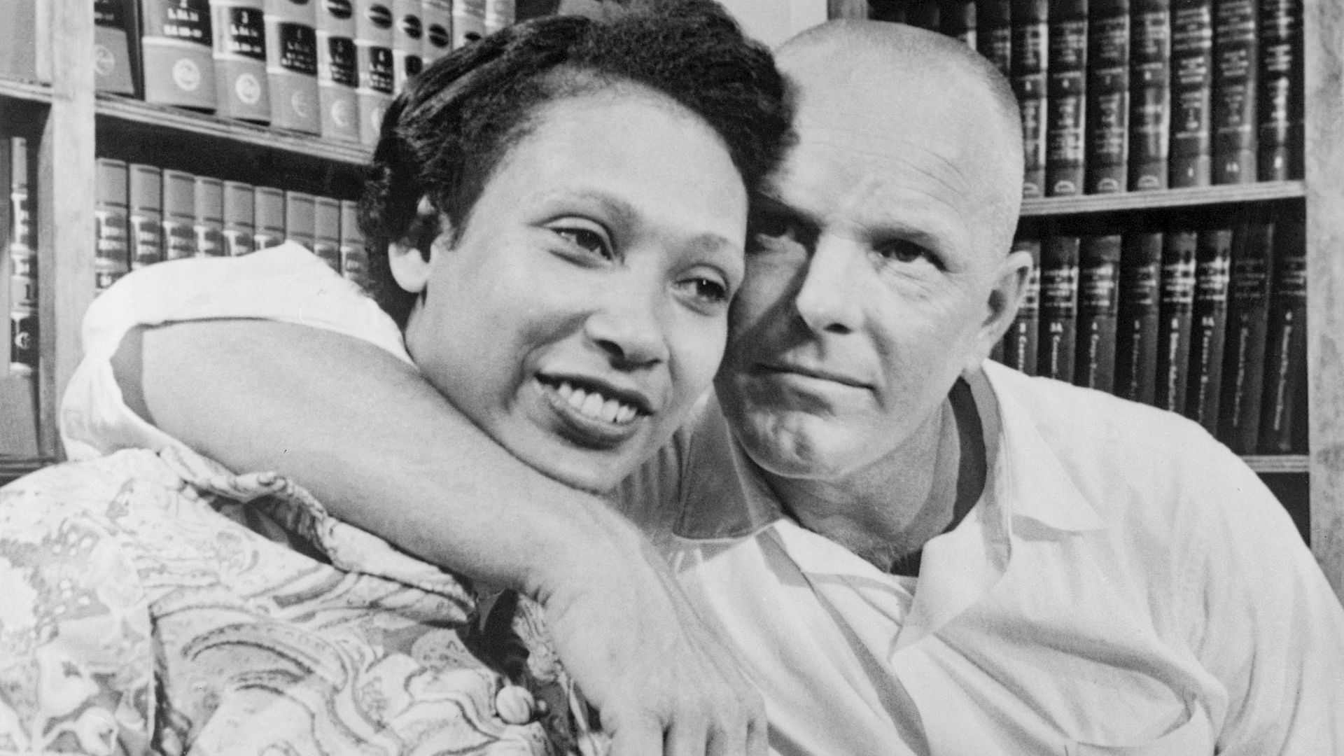 Mildred and Richard Loving, photographed in 1967. He has his arm around her and they're sitting in what looks like a law office. 