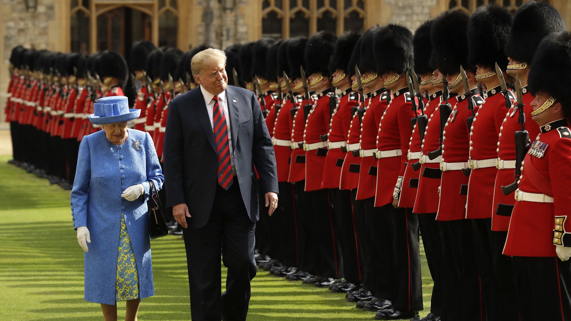 Trump, next to the Queen, walks past a line of guards in British uniform