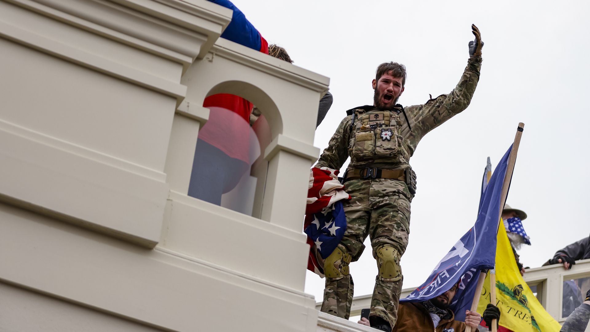 Photo of a man in military gear raising his arm 