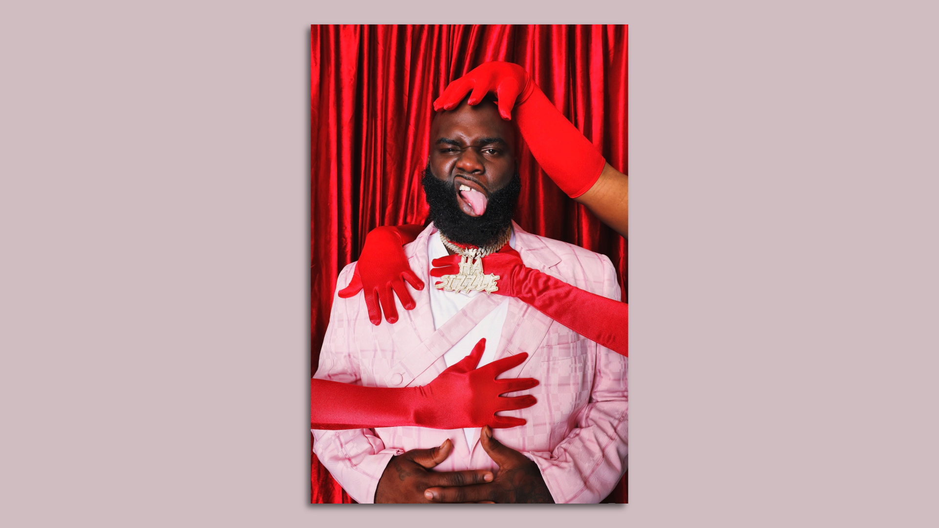 A headshot of New Orleans artist Ha Sizzle. He sticks his tongue out and is embraced by two sets of red-gloved hands belonging to unseen people.