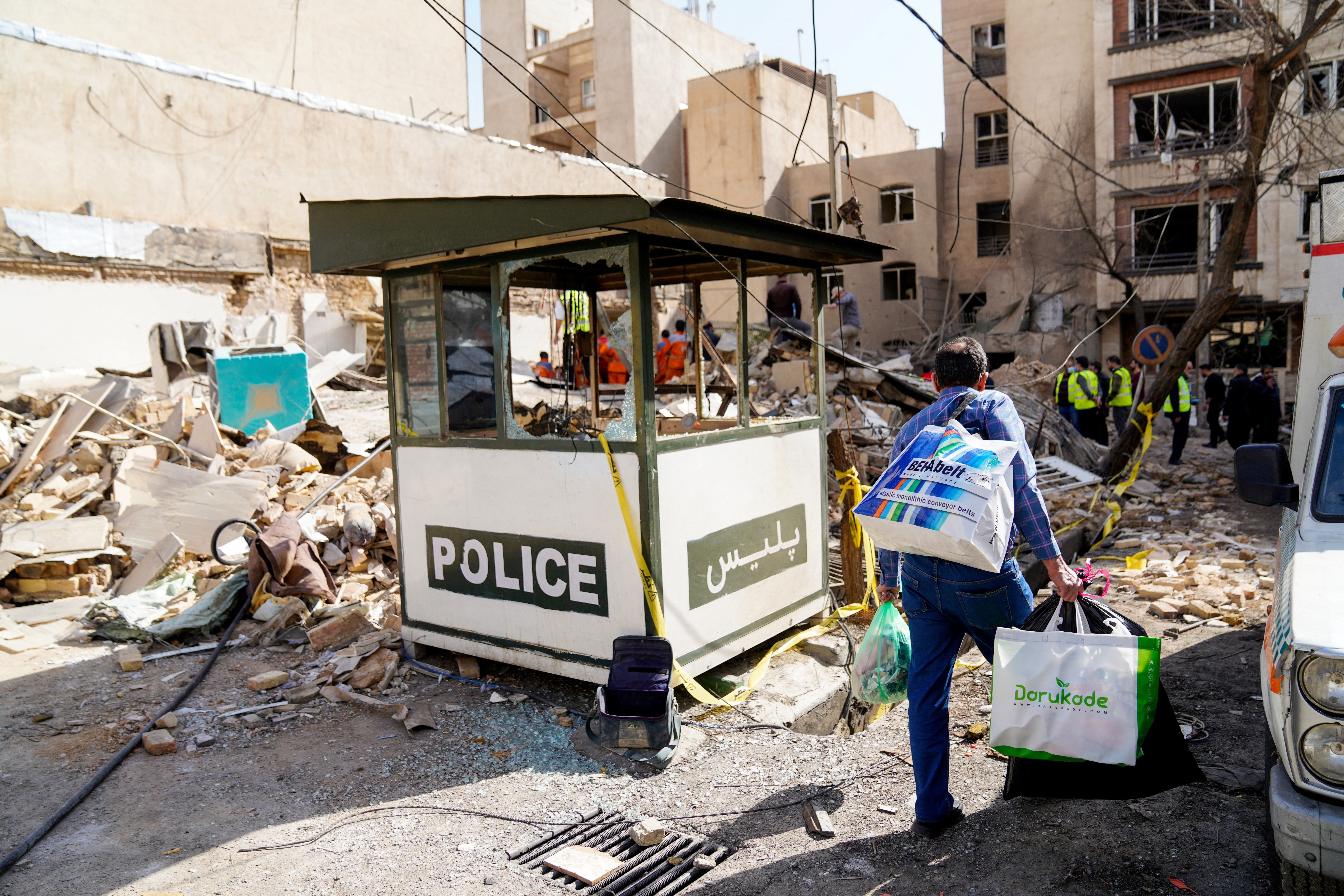 This picture obtained from Iran's ISNA news agency, shows an Iranian man carrying bags as he walks past debris from a destroyed building following a missile strike on a neighborhood of the Iranian capital Tehran on February 28, 2026. 