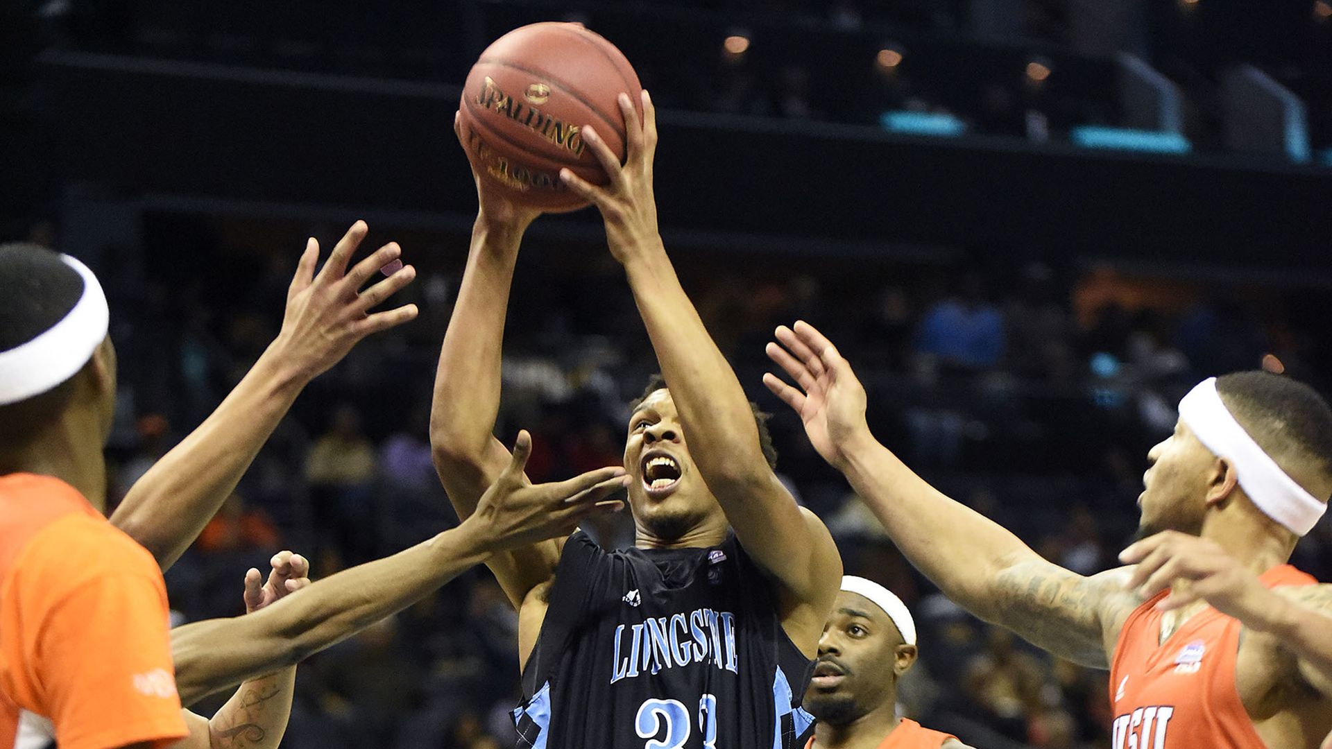 basketball player shoots for a basket while other players block