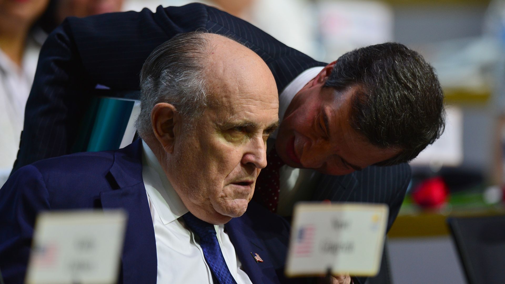 An aide whispering in Rudy Giuliani's ear