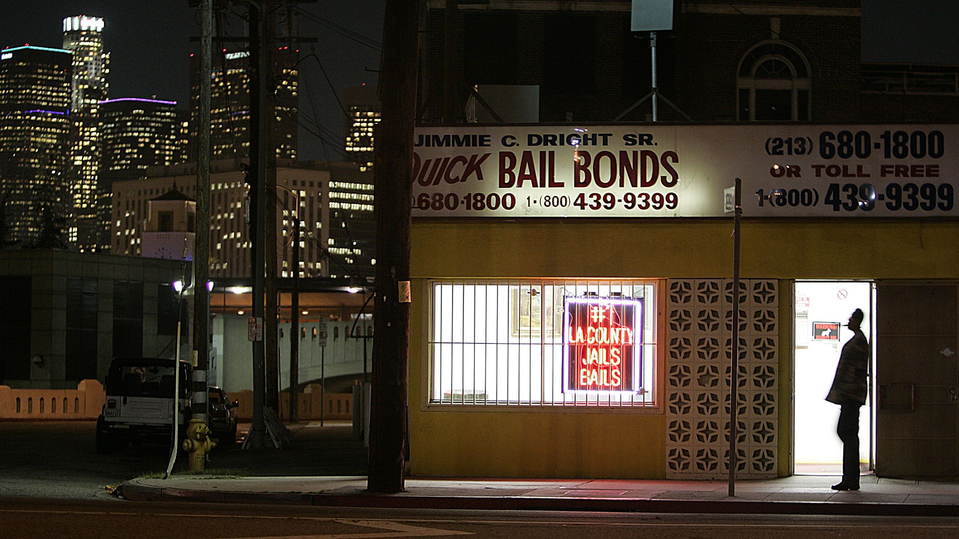 The lights of downtown Los Angeles shine behind the Quick Bail Bonds building on Vignes Street across from Men's Central Jail