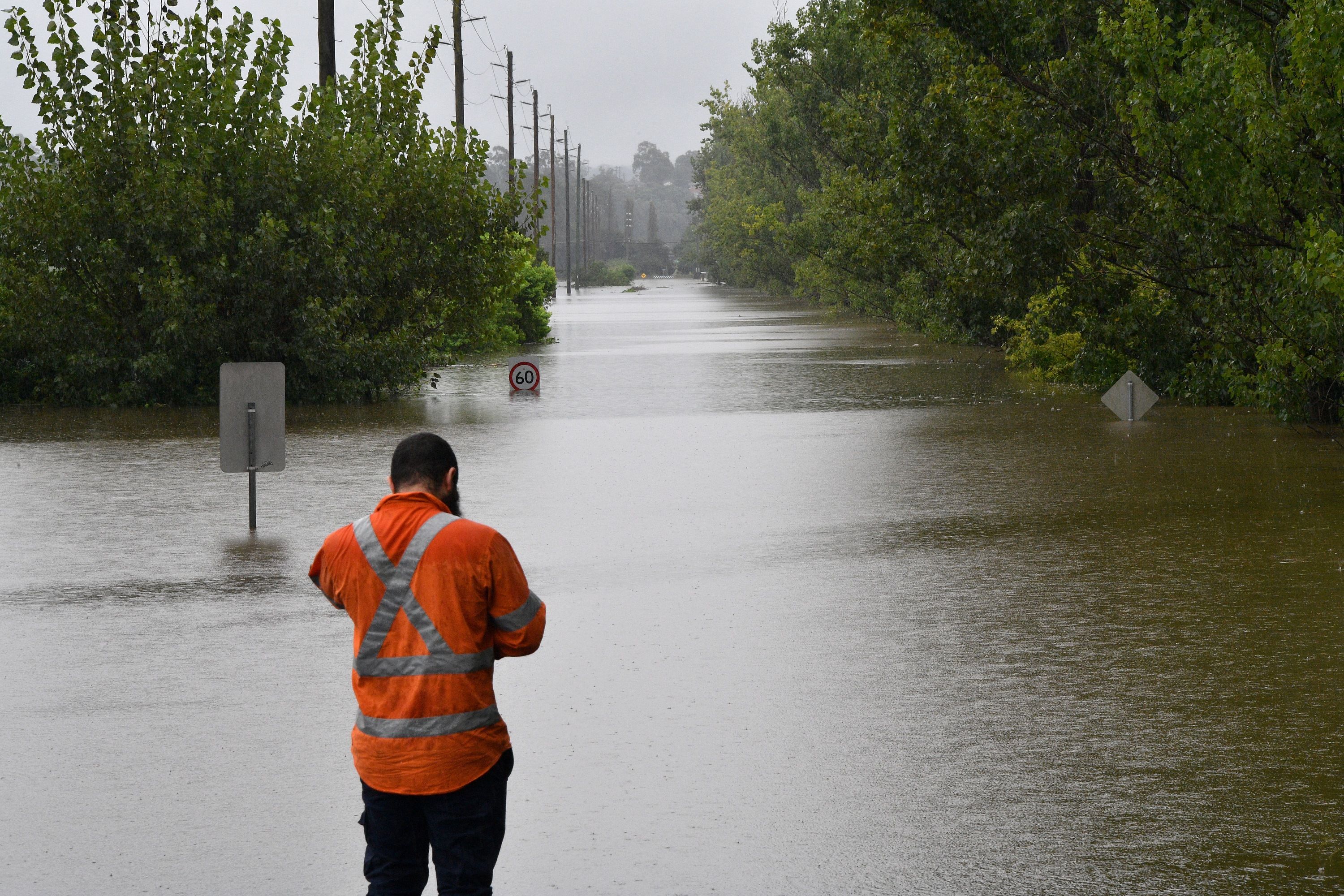 A worker looks at an inundated main road by floodwaters in Richmond suburb on March 22, 2021, in Sydney