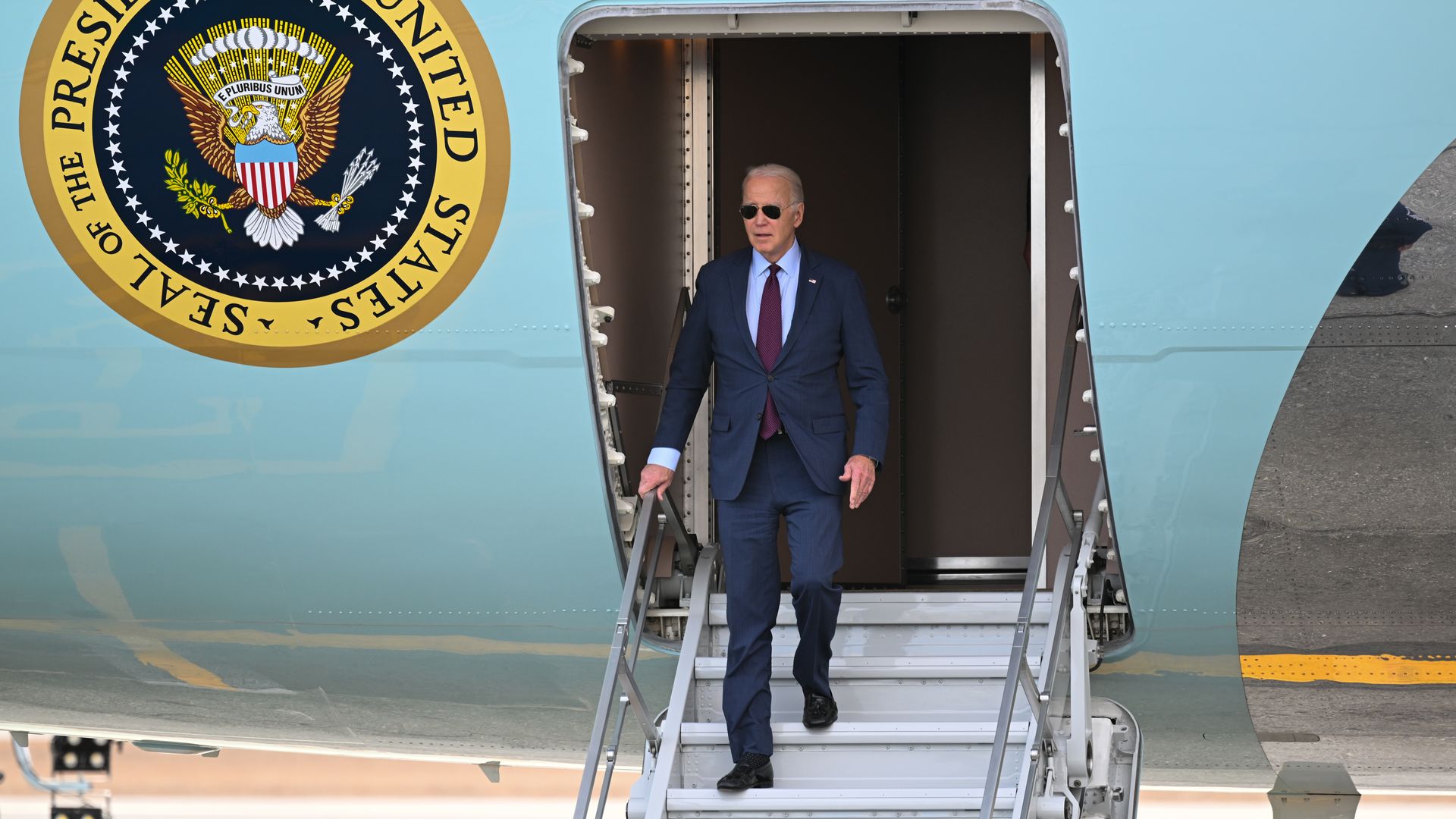 President Biden exits Air Force One by walking down a short staircase.