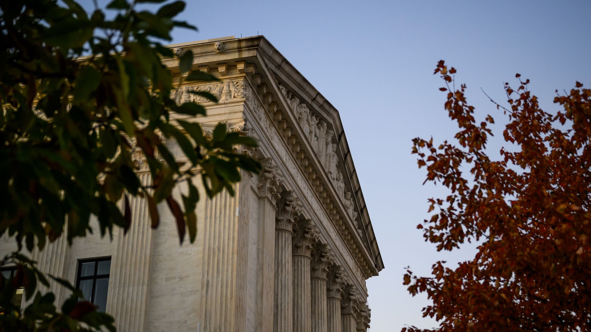 A side view of the Supreme Court surrounded by trees can be seen in this photo.