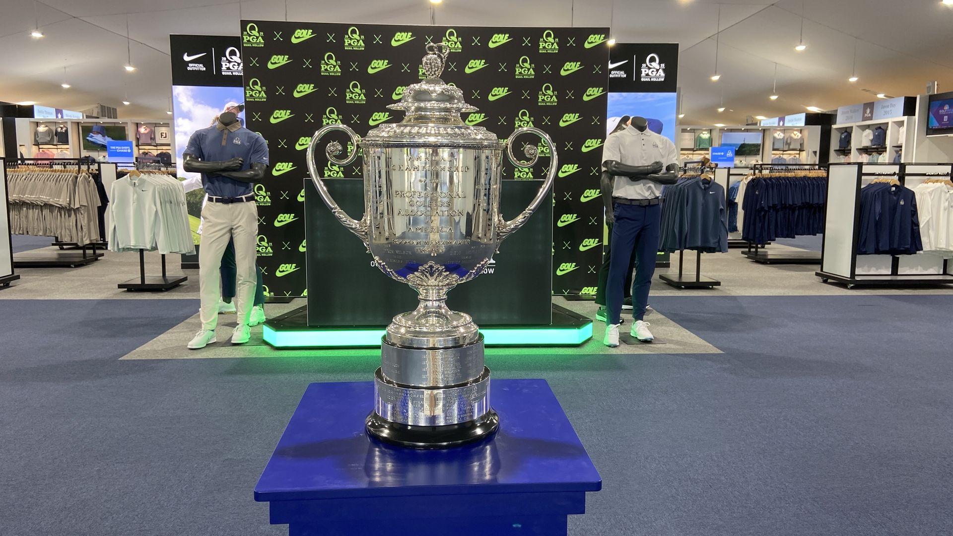 PGA Championship trophy in the PGA Shops at Quail Hollow with golf apparel behind it. 