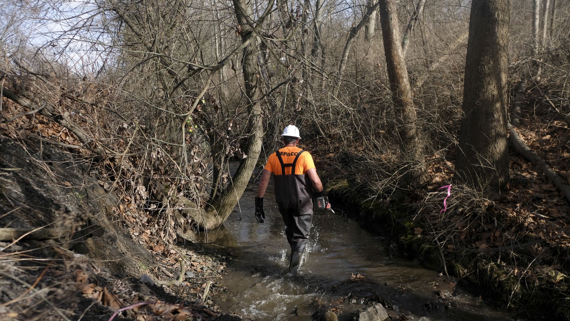 A member of the Environmental Protection Agency (EPA) takes water samples from Sulphur Run creek following a train derailment