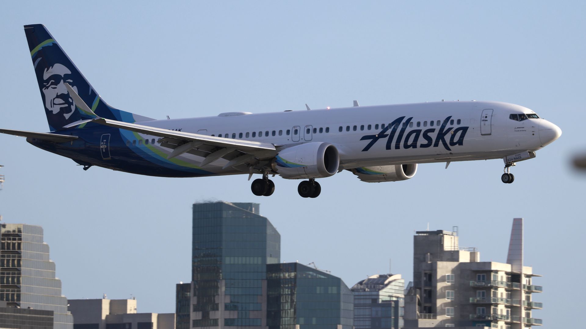 An Alaska Airlines Boeing 737 MAX 9 aircraft flies by residential and commercial buildings approaches San Diego International Airport