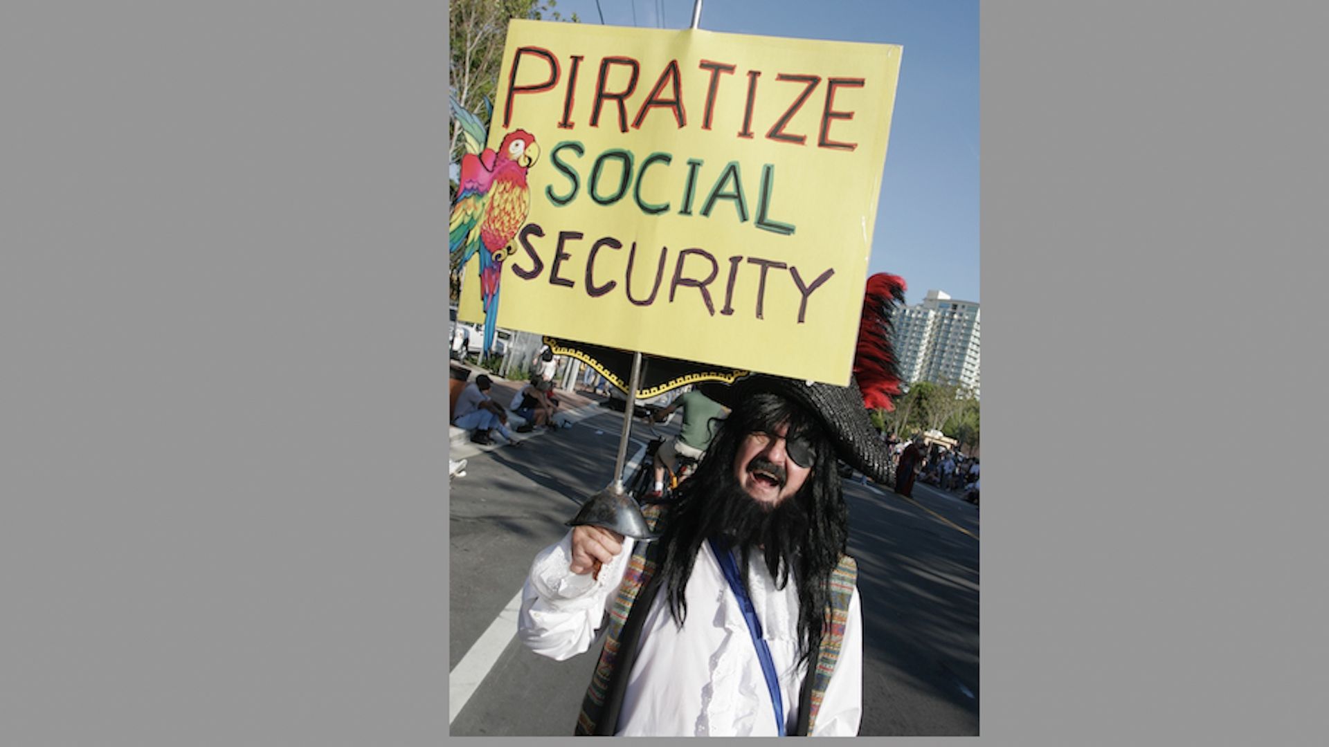 A person dressed as a pirate holds a sign saying "Piratize social security"
