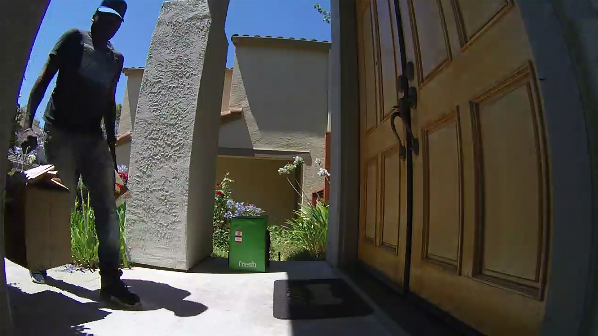 A man carrying a shopping bag walks up to a front door