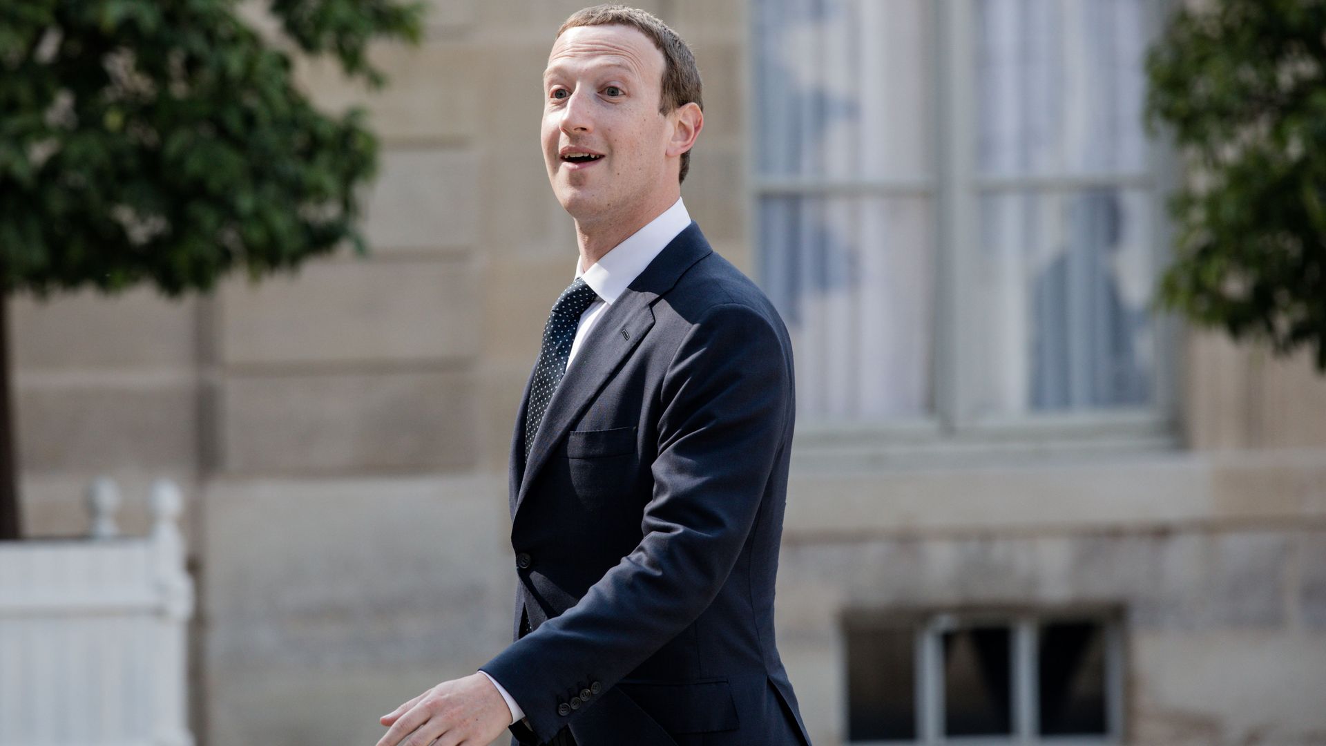 Mark Zuckerberg in a suit walking outdoors