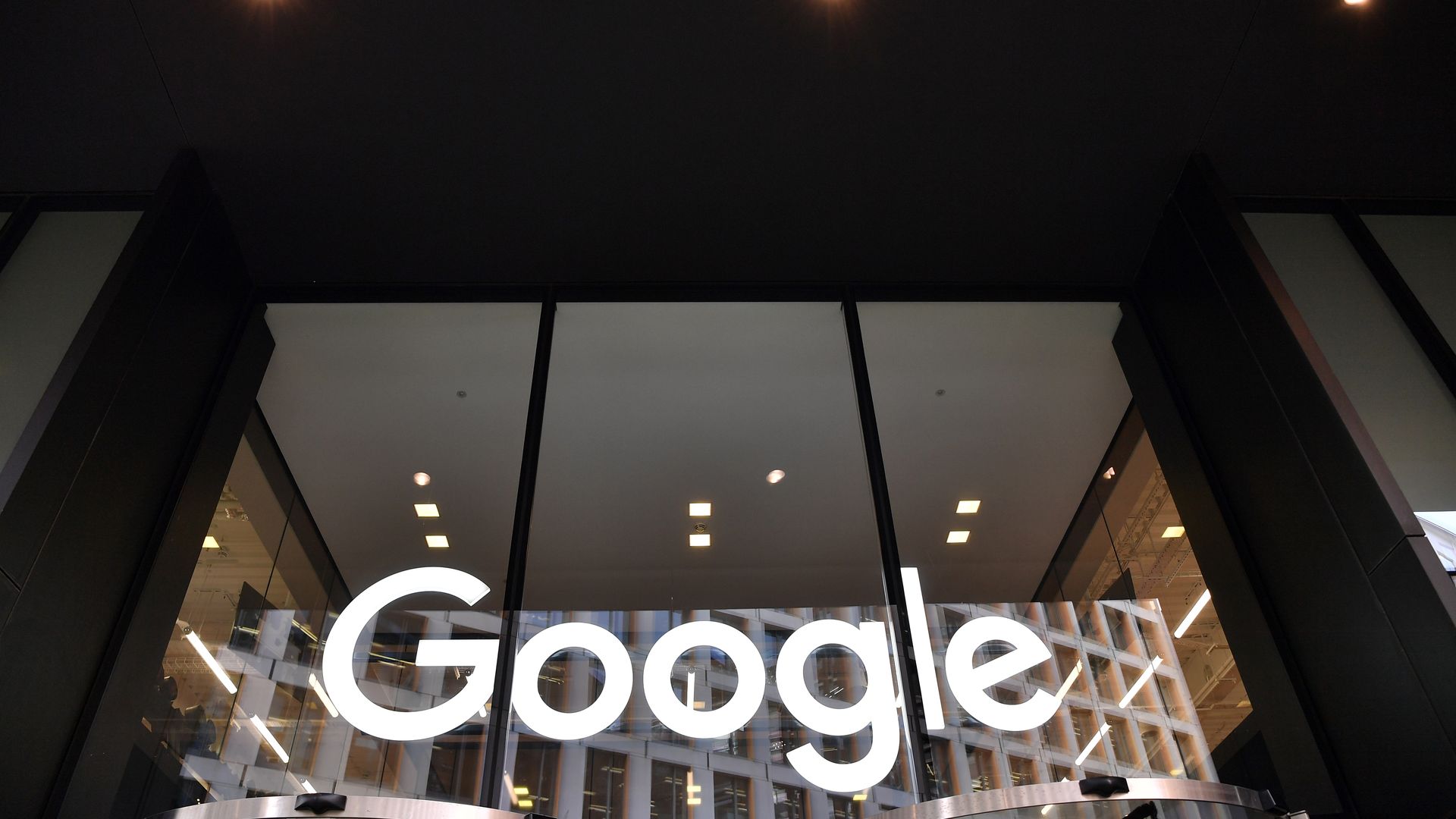 In this image, the white Google logo is seen at the bottom of three large glass windows on the side of a building.