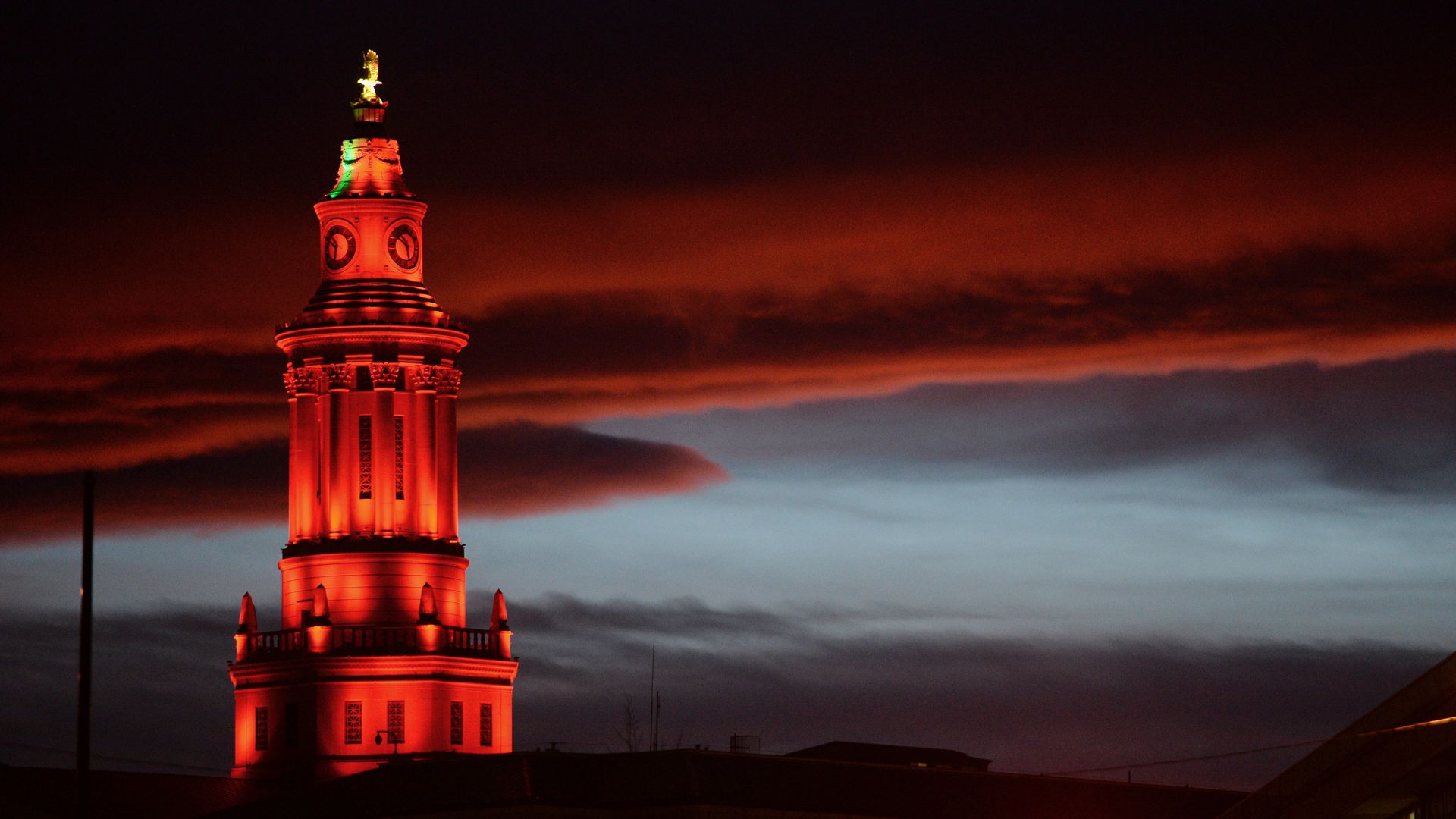 A photo of the top of the Denver City Hall building lit up in red