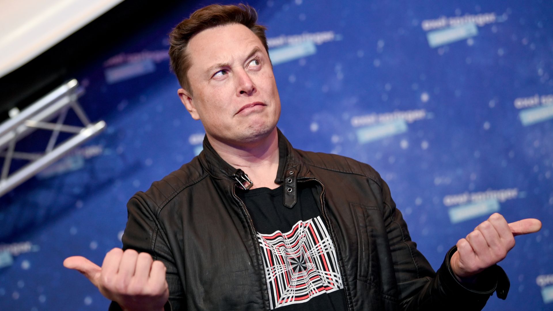 Elon Musk making a confused face with his thumbs pointing in opposite directions