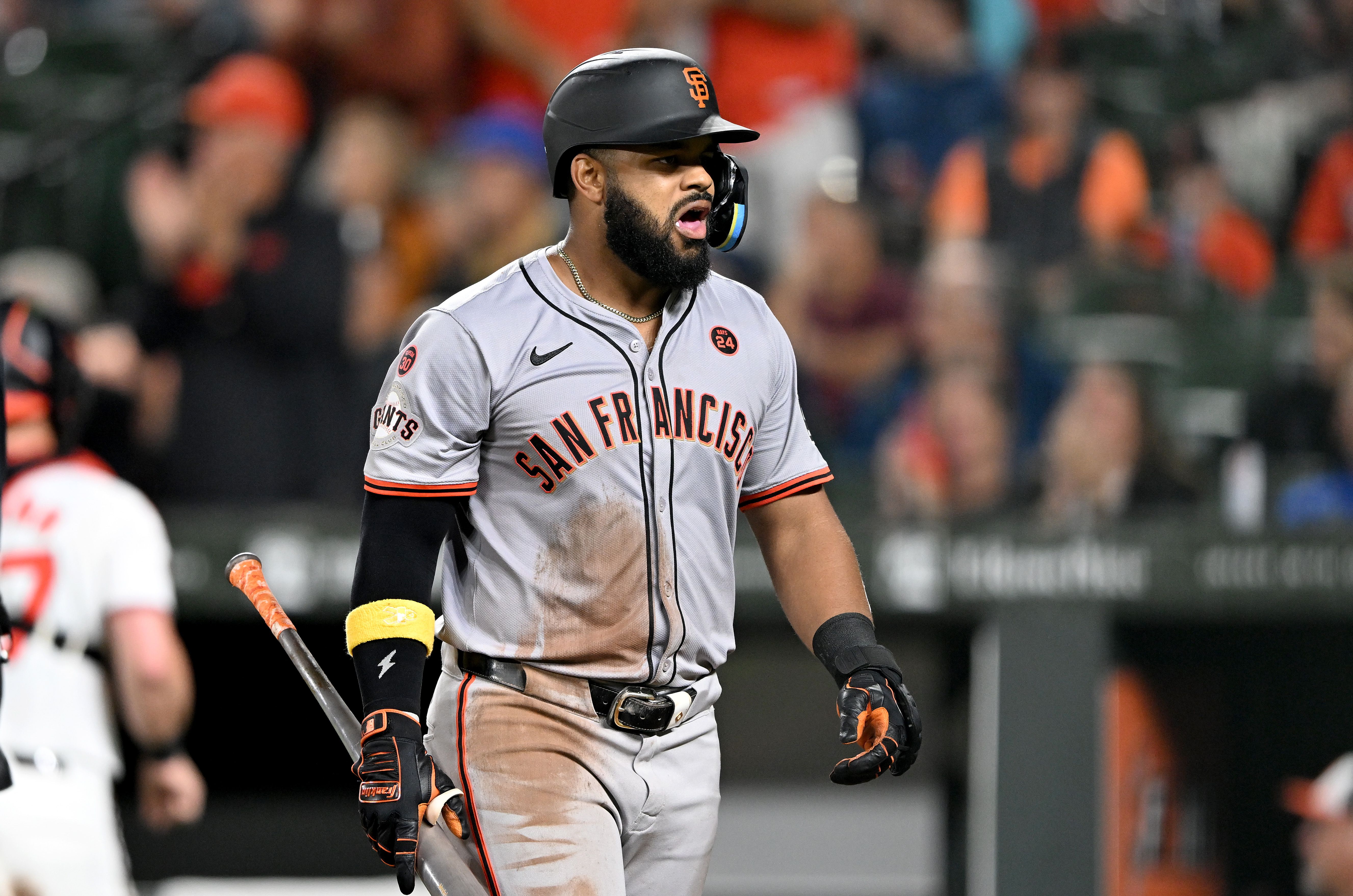 A man in a gray baseball uniform reacting after striking out