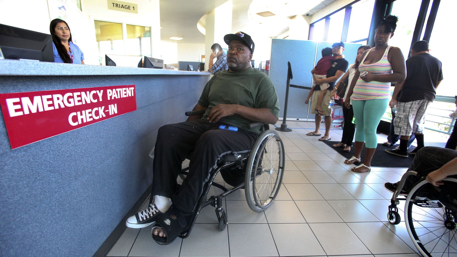 A man in a wheelchair checks in a hospital emergency room.