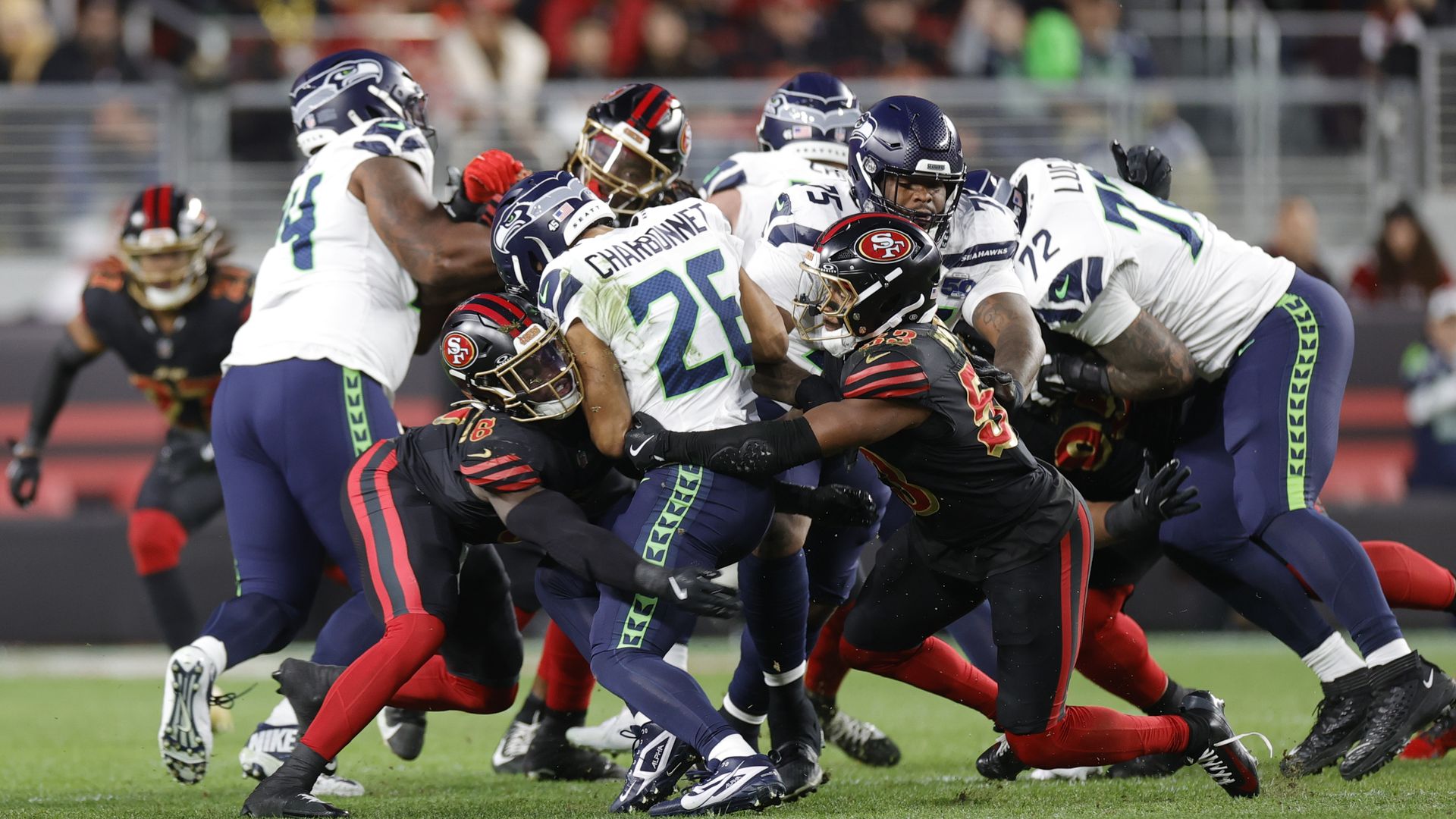 A group of football players from two teams clash on the field. 