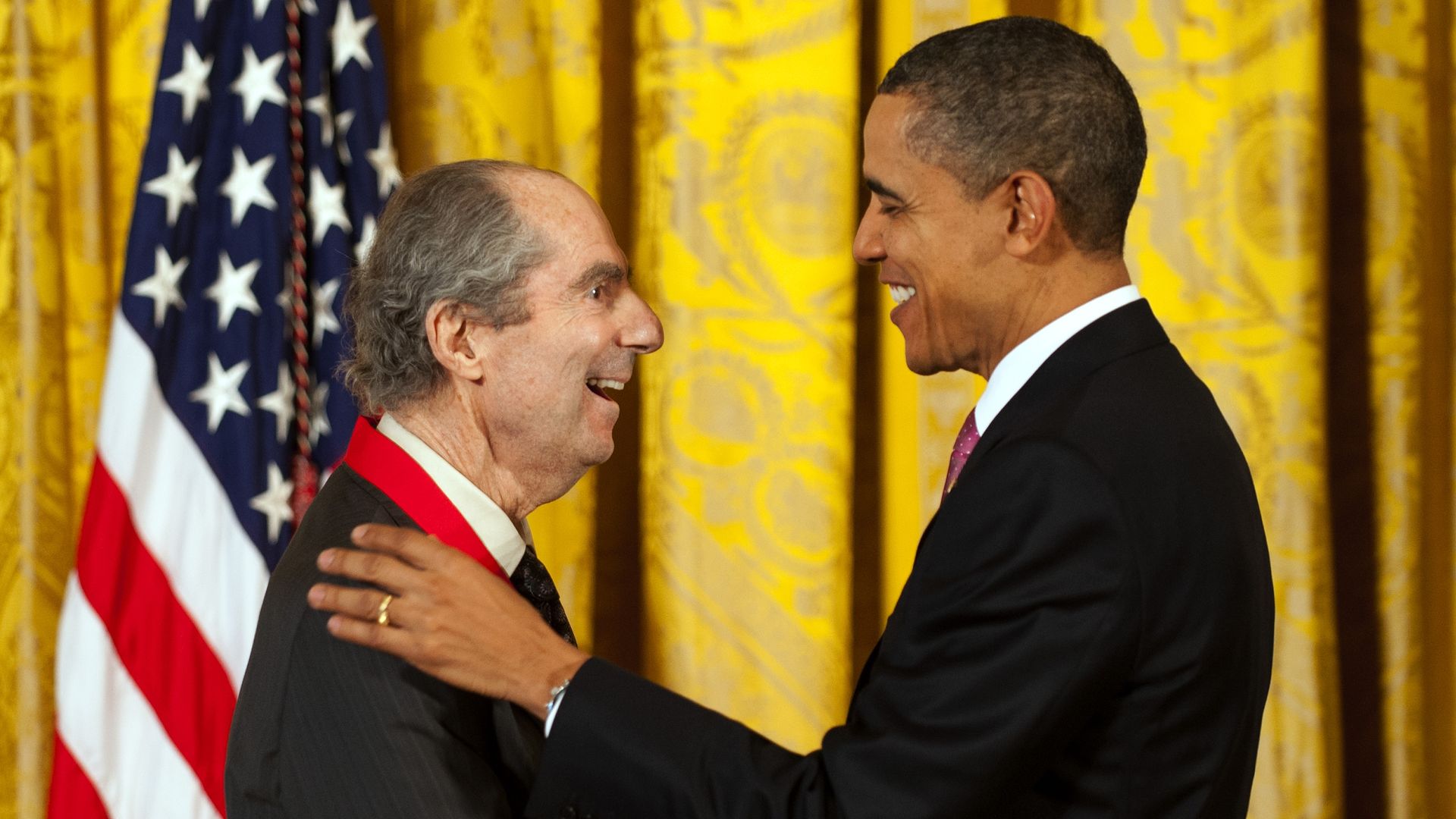 Obama places his hands on Roth's shoulders