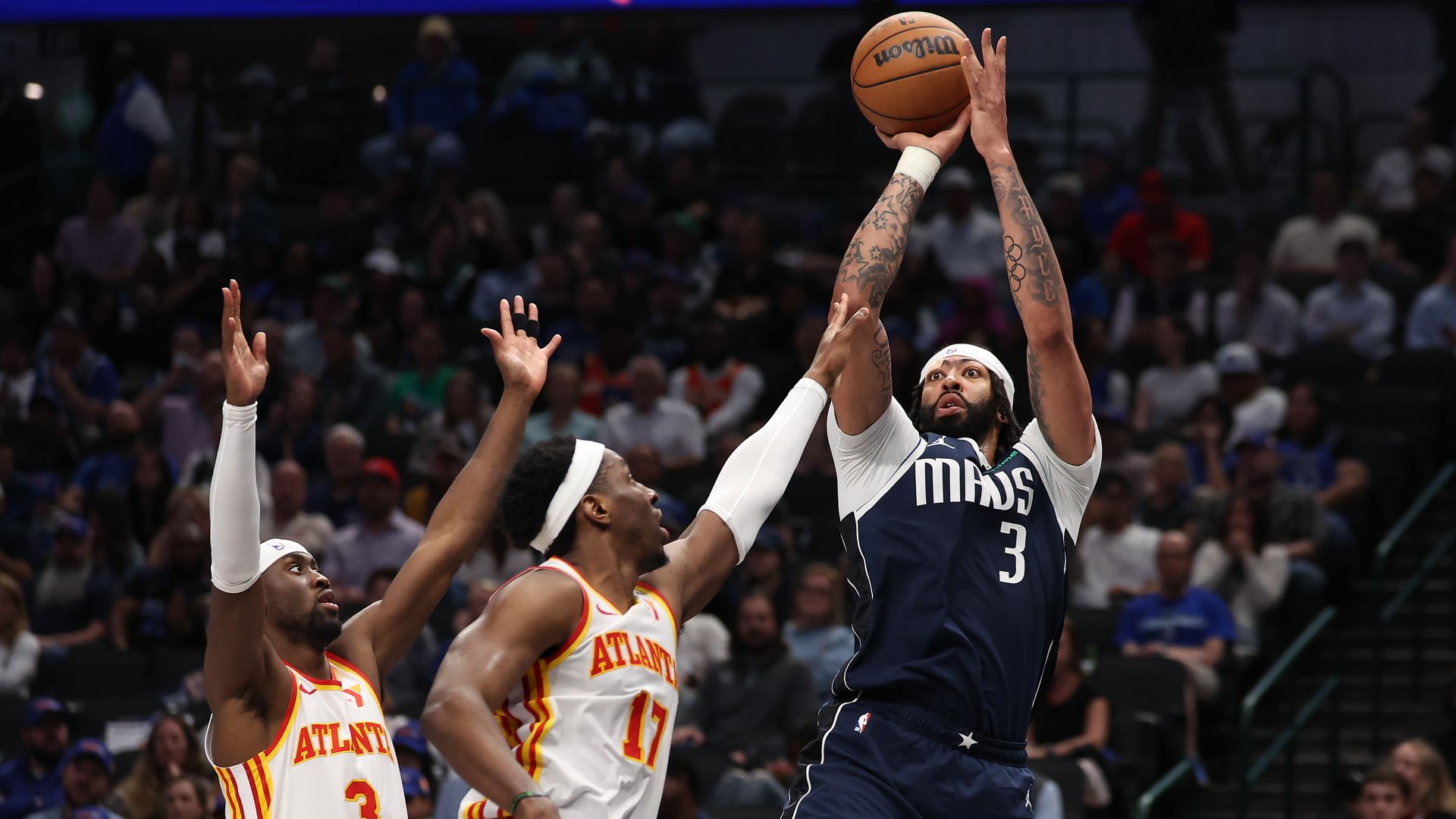 A photo of two Atlanta Hawks players trying to stop Anthony Davis from shooting a basketball for the Dallas Mavericks. 