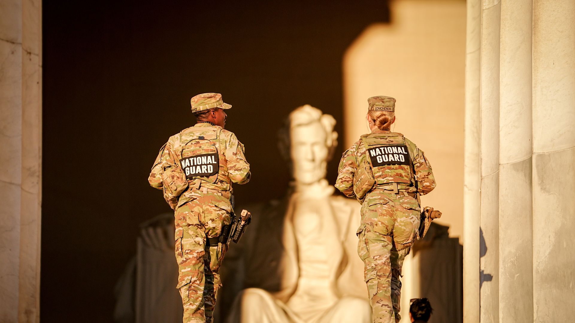 Two members of the National Guard in uniform walk up the steps of the Lincoln Memorial. 