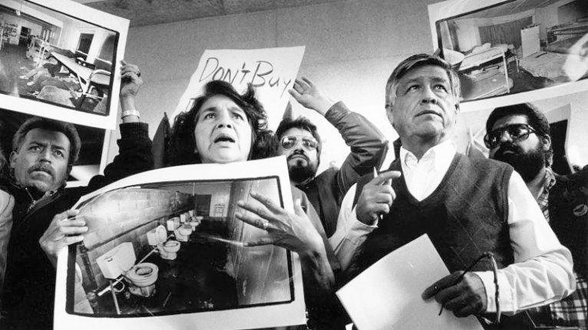United Farm Workers leaders Dolores Huerta and Cesar Chavez display photos of the conditions that farmworkers endure in San Joaquin Valley farm labor camps at a news conference outside U.S. District Court in Fresno, California, on Nov. 21, 1989. (Richard Darby/Fresno Bee file/Tribune News Service vi