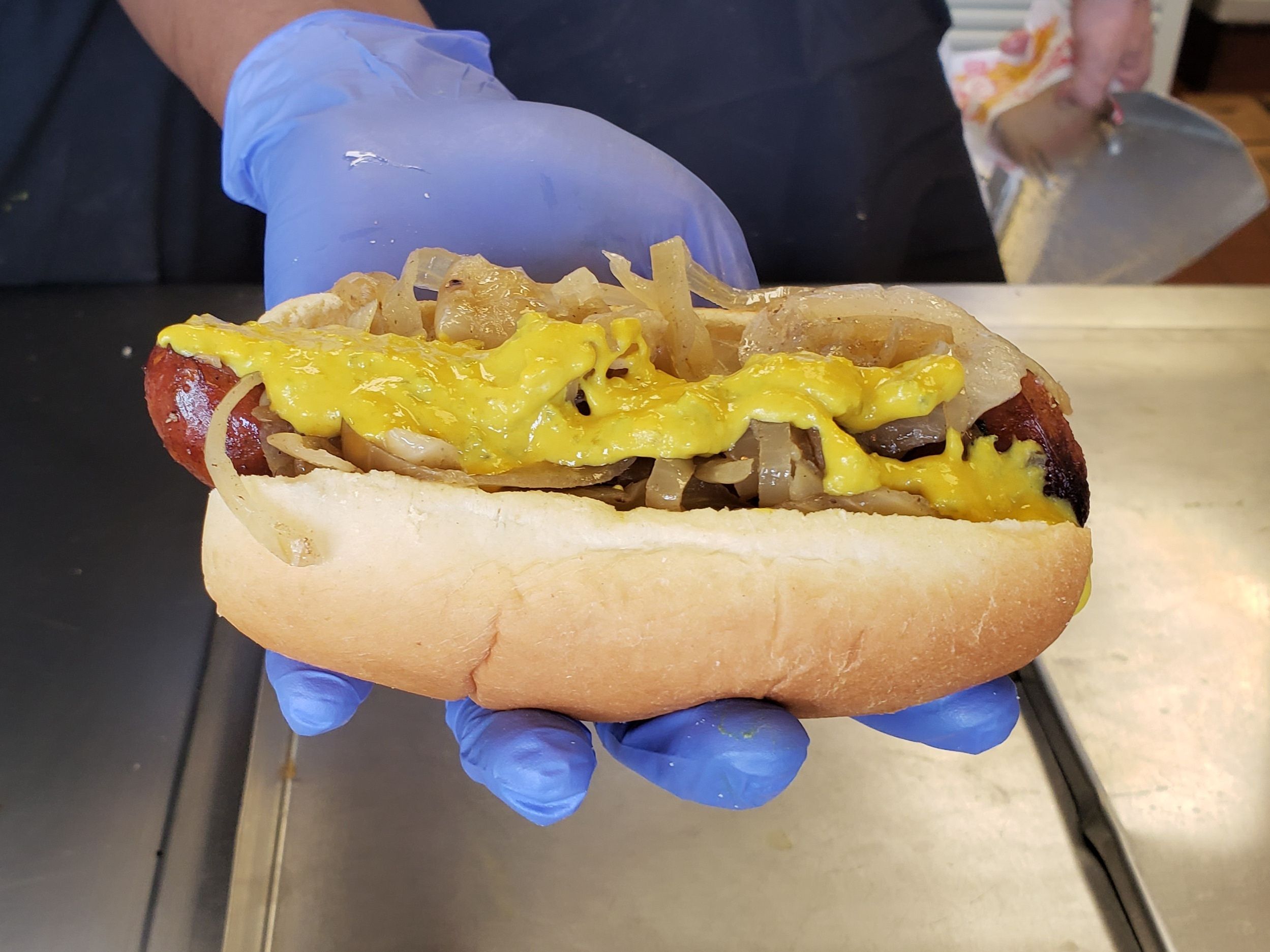 Photo of a polish sausage with onions and mustard on it 
