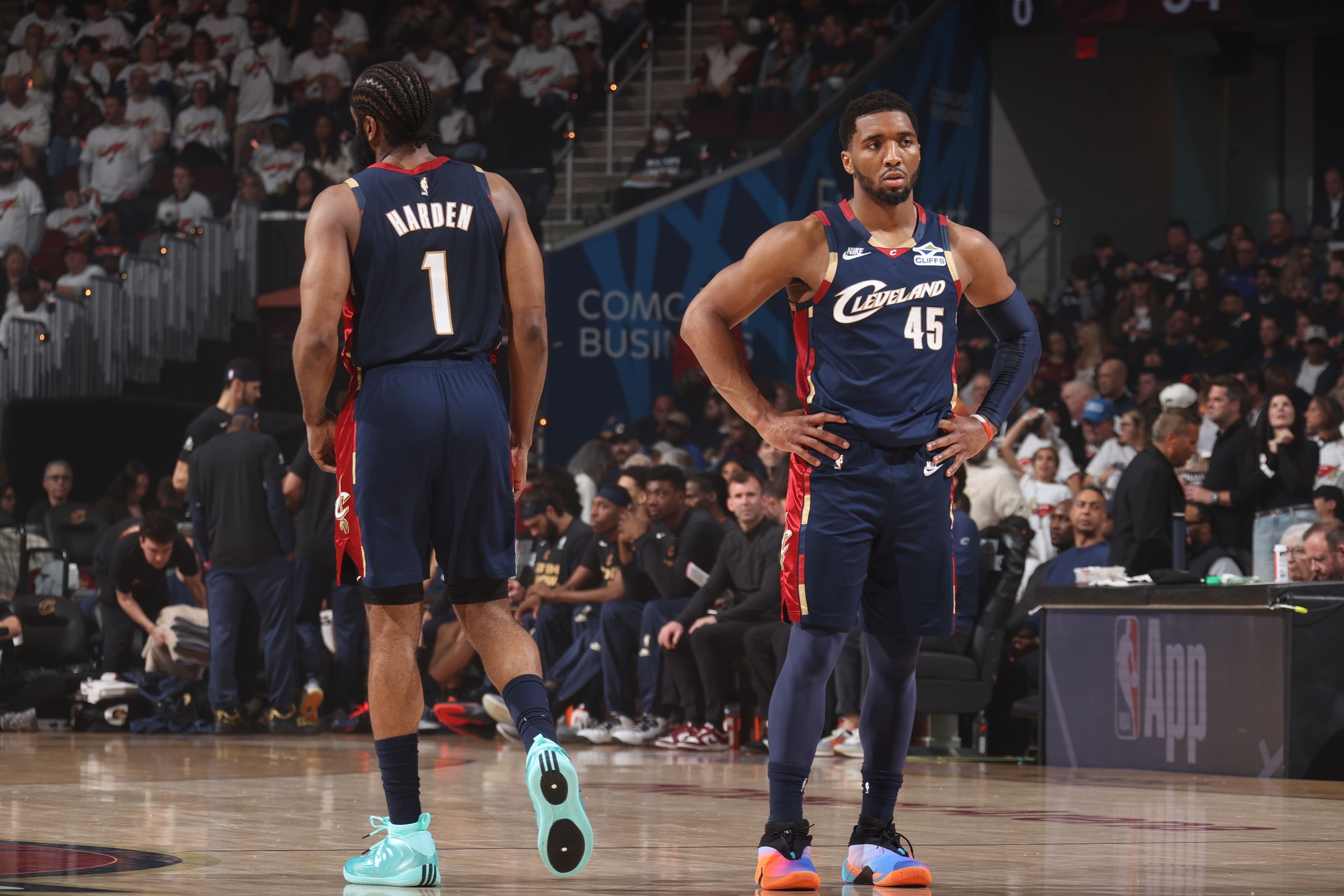 Two Cavaliers players on a basketball court during a game: one with back to camera wearing jersey HARDEN and number 1, the other facing forward in navy with number 45; crowded arena in background.