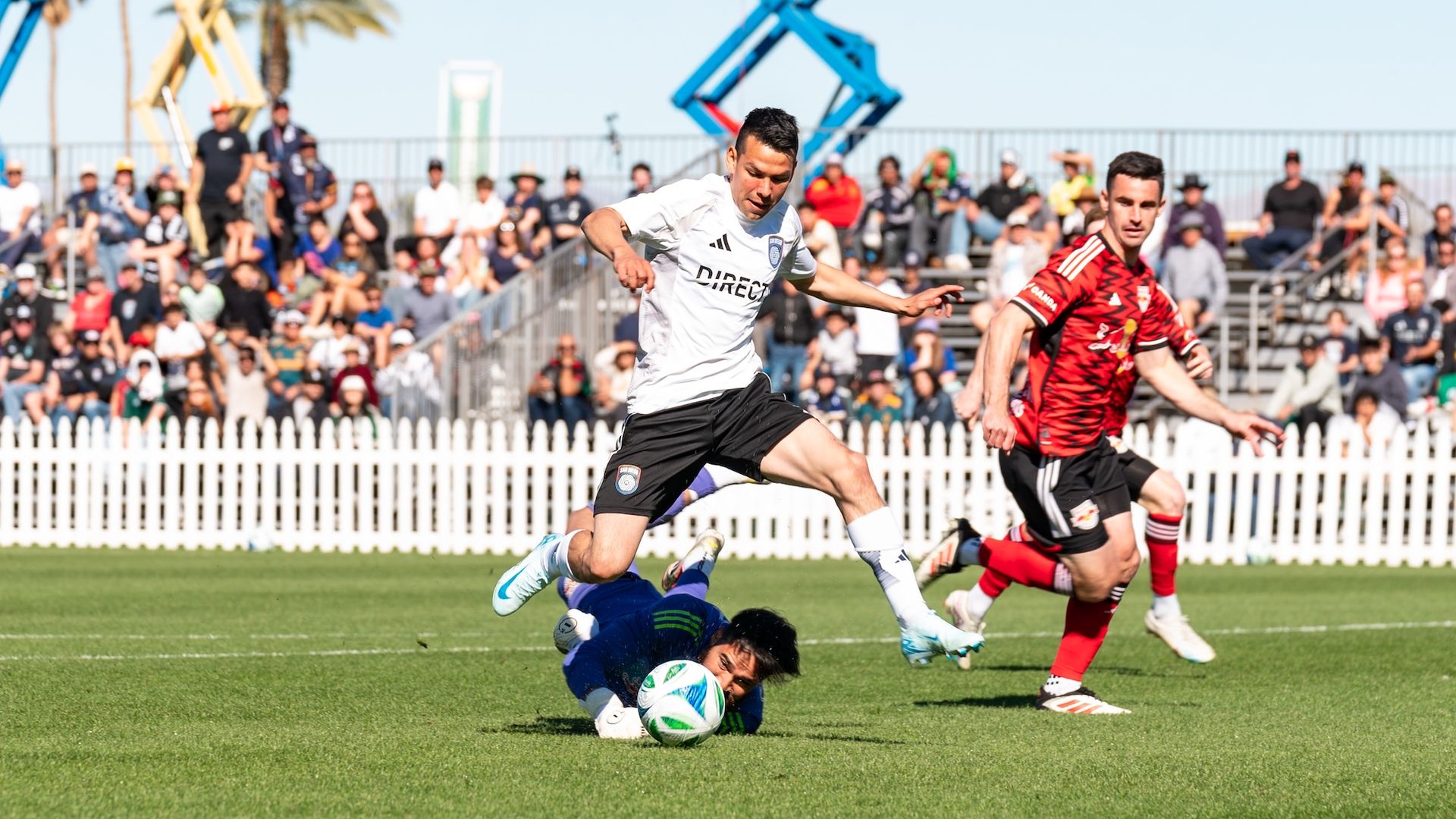 A soccer player dribbles past the goalie during a game with a defender behind him.