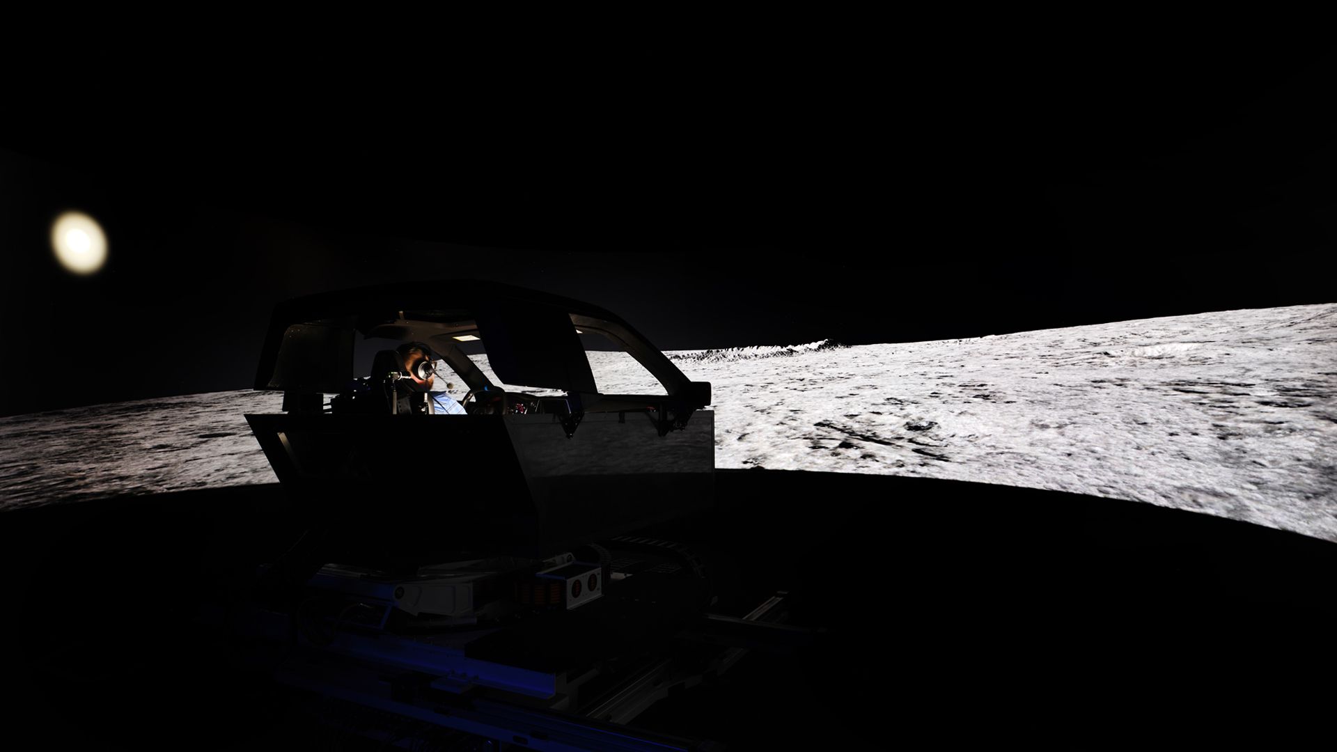 Image of a person in a simulator, driving on the surface of the moon. 