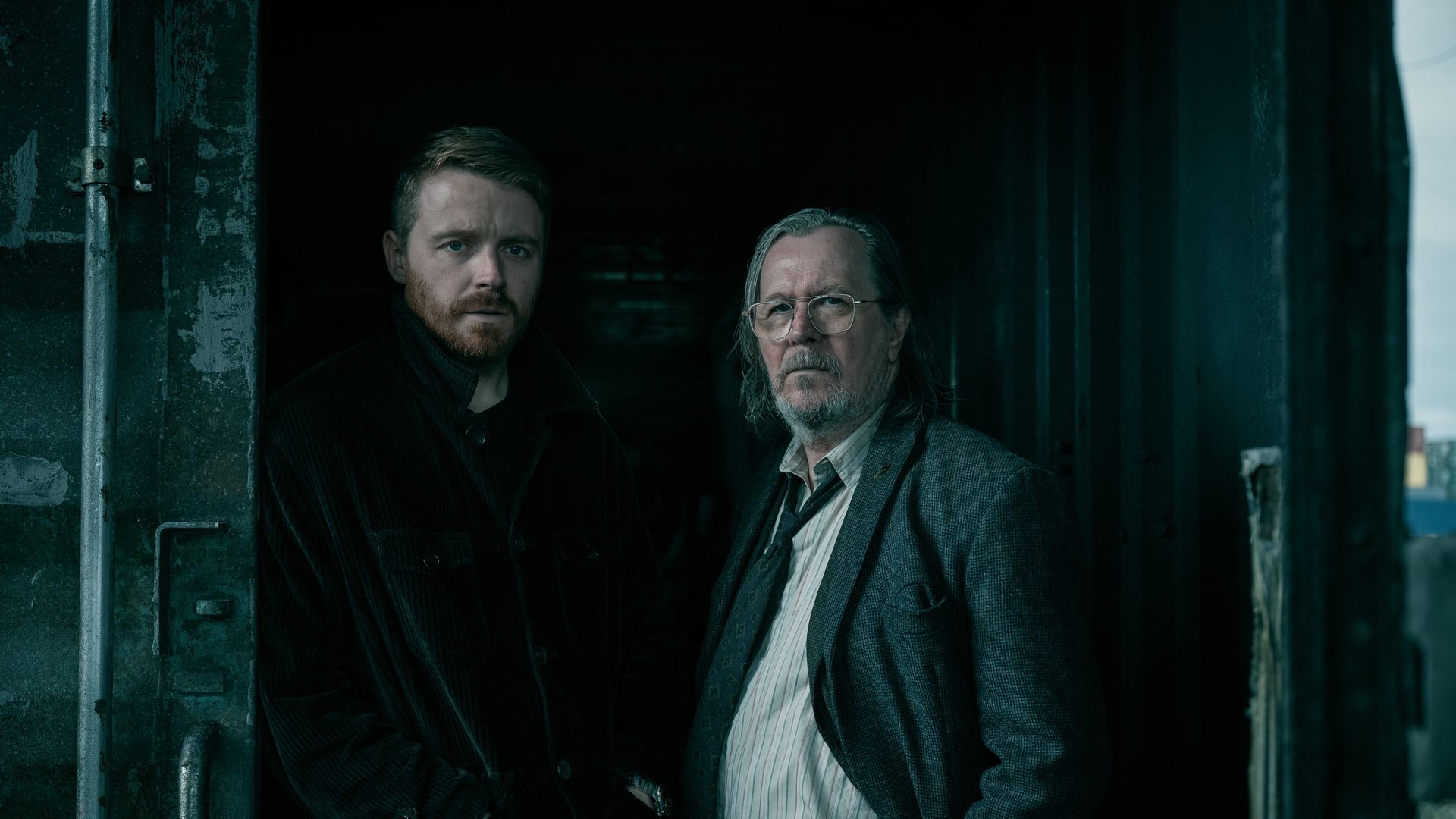 Jack Lowden and Sir Gary Oldman, stars of "Slow Horses," stand in a dark doorway
