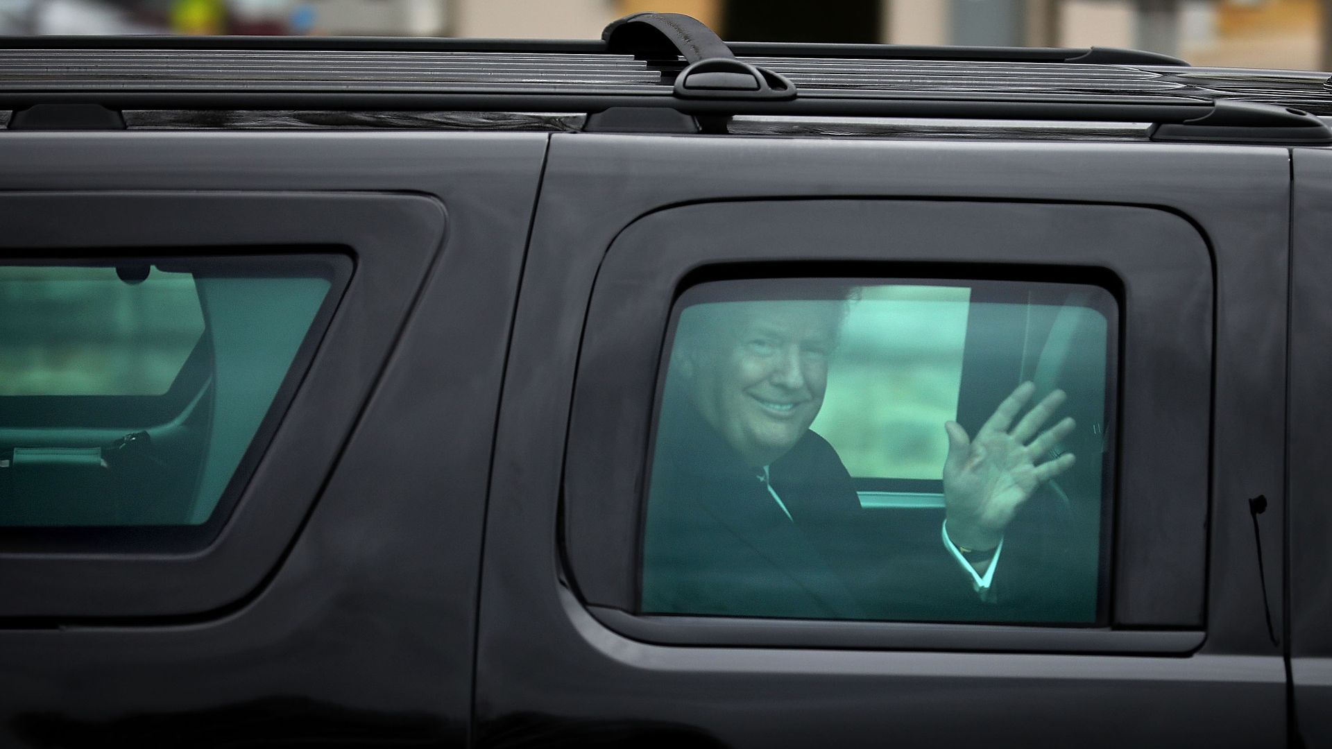 President Trump waves from inside his car