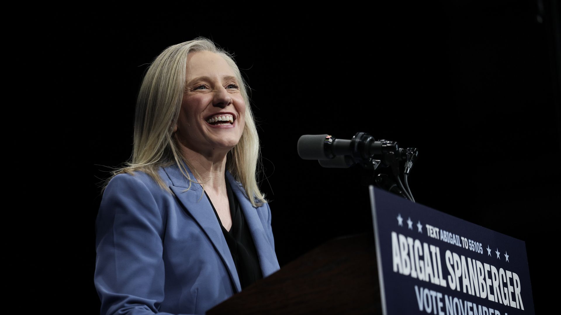 Abigail Spanberger speaks behind a microphone and a campaign sign.