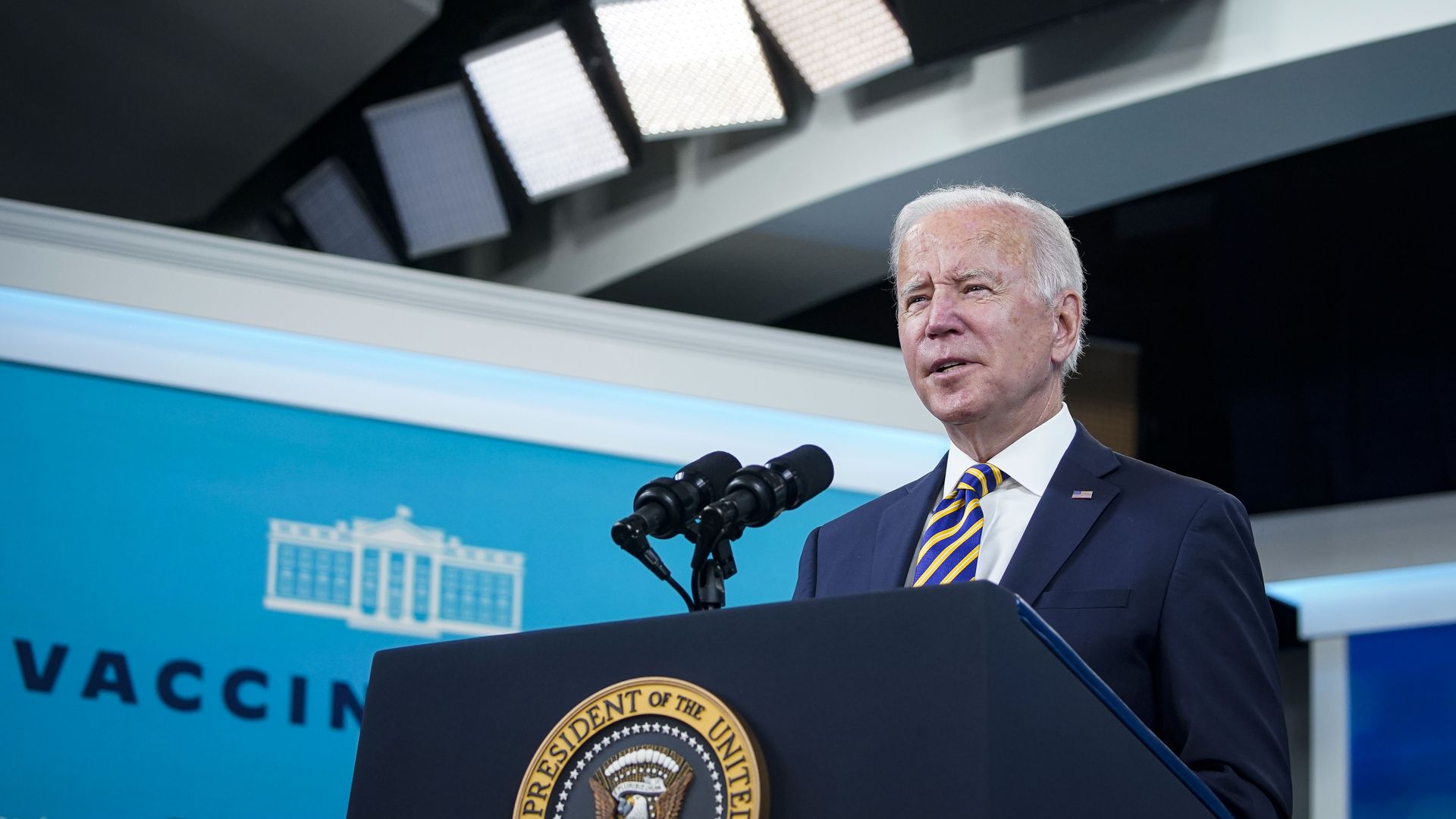 Photo of Joe Biden speaking into a mic at a podium with the White House seal