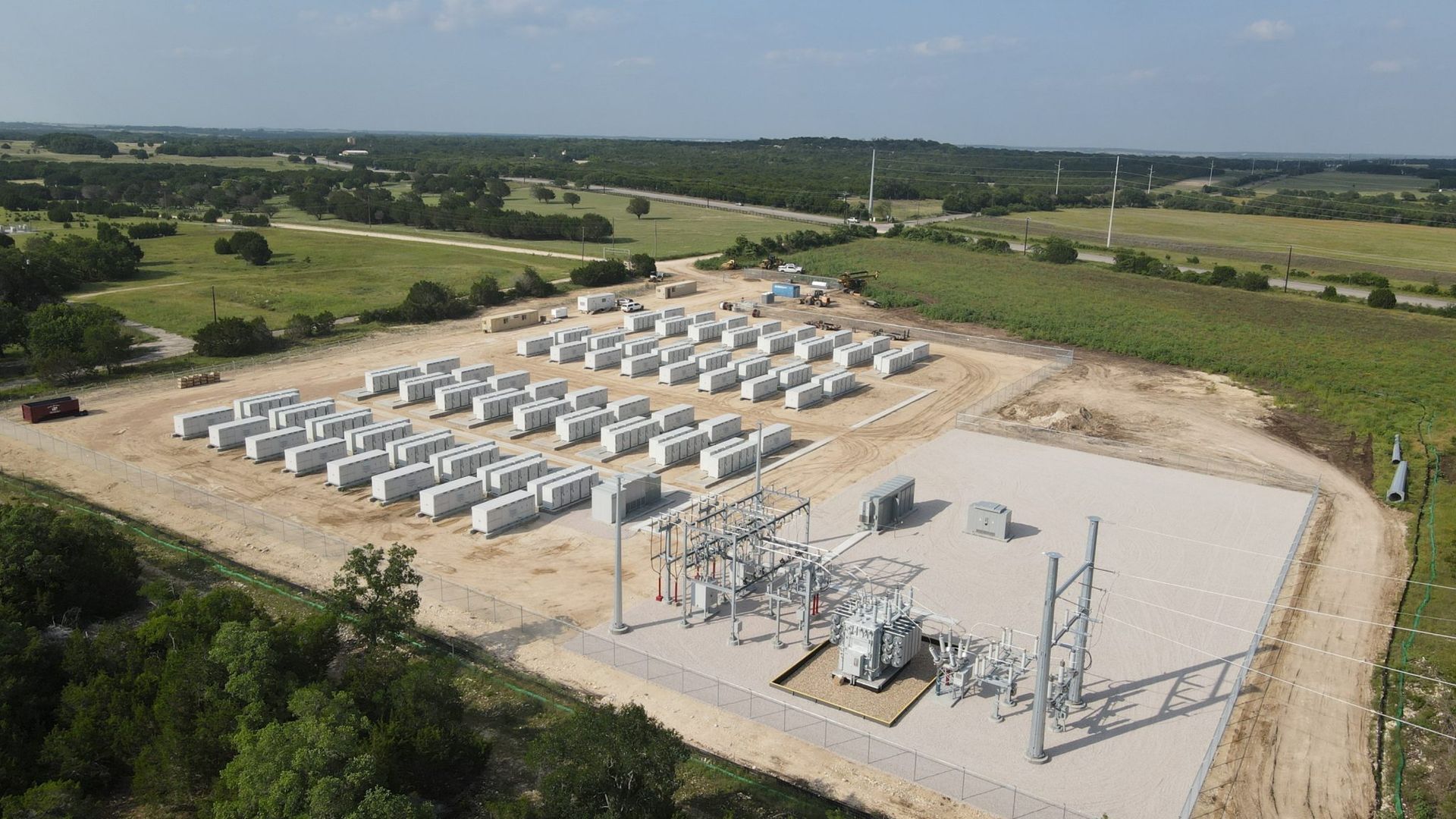A collection of battery storage devices near a power substation. 