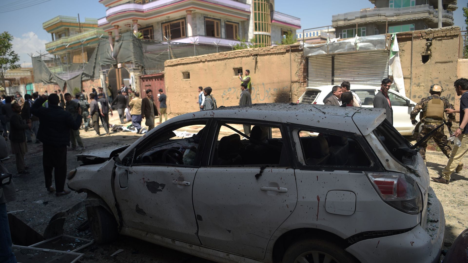 A burned-out car and crowds in the street where the bombing took place