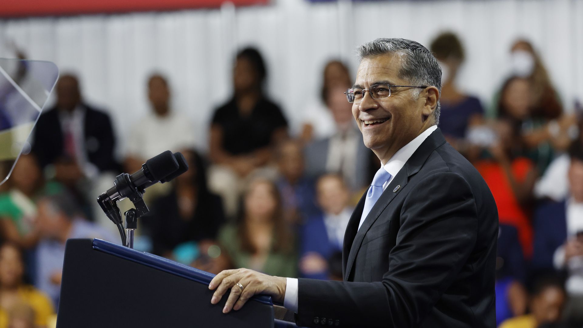 Xavier Becerra speaking in front of a lectern and teleprompter at a campaign rally