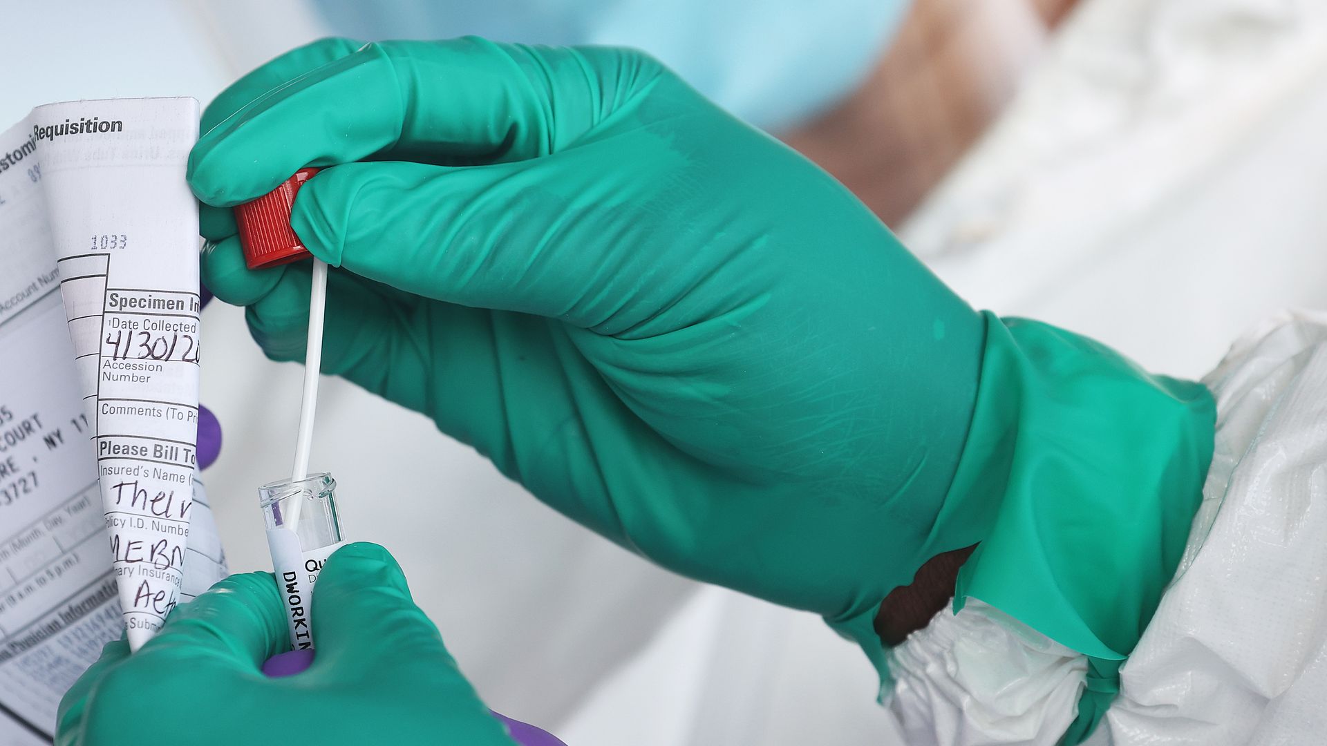 A person holding a COVID test in gloves.