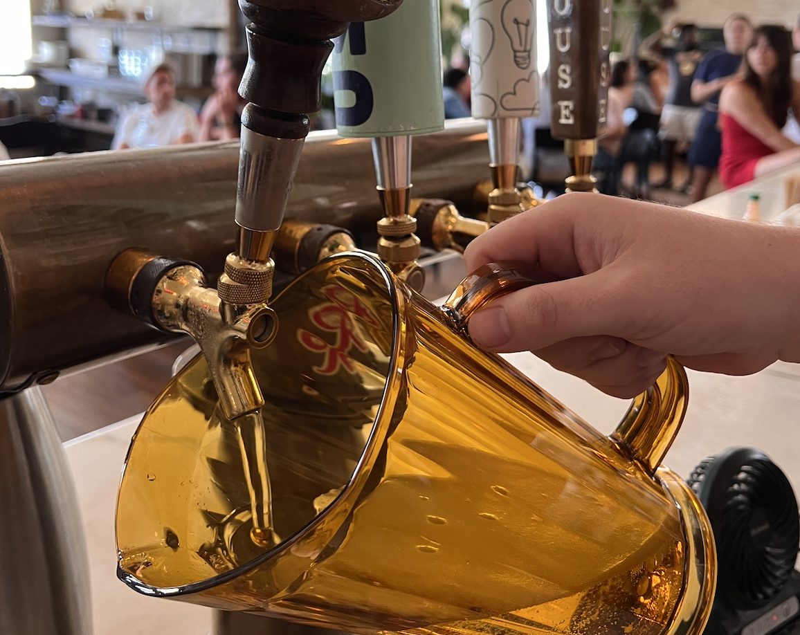 A pitcher held underneath a spout.