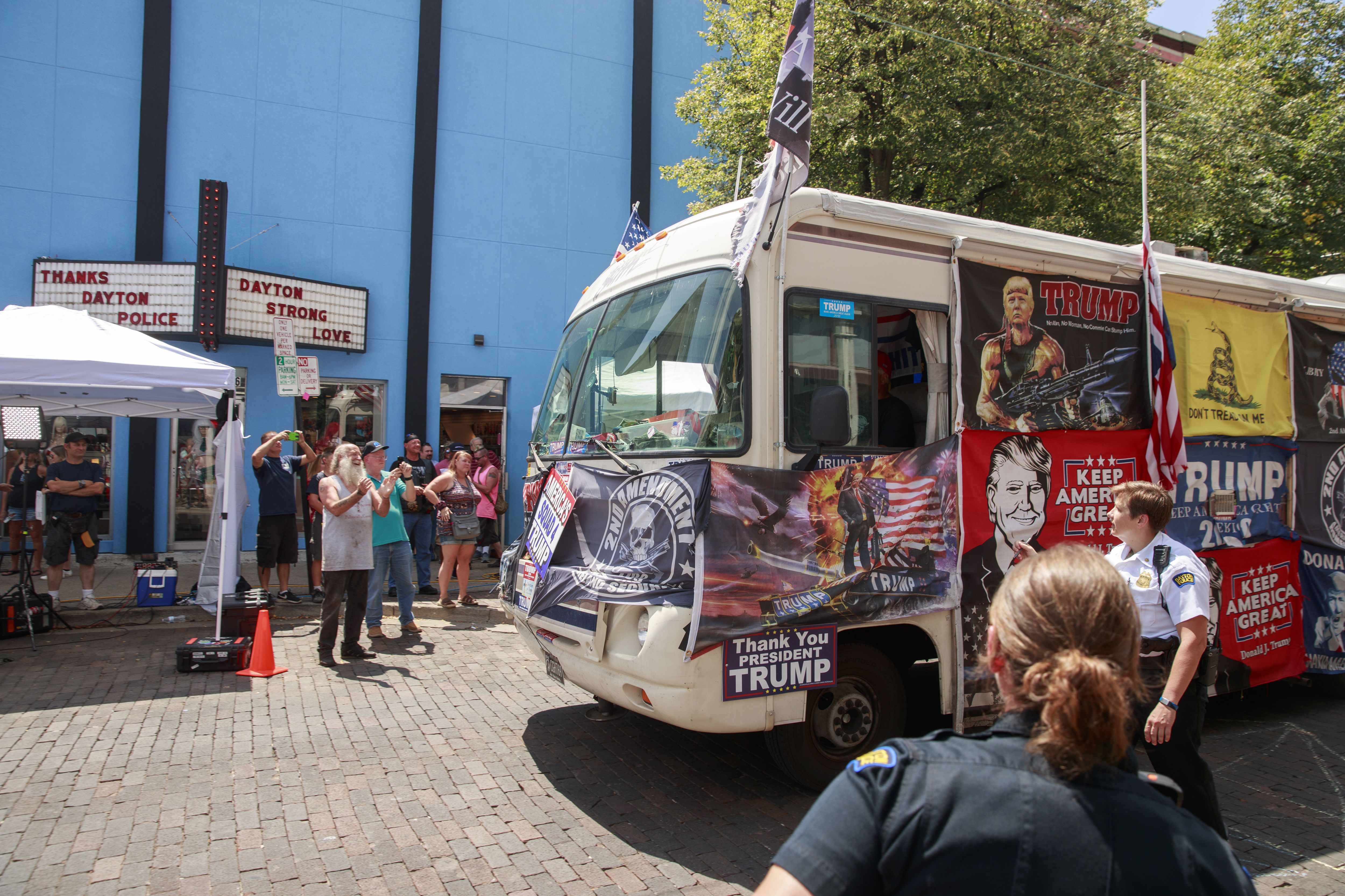 A Trump supporter drives a bus with flags supporting Trump down 5th Street at the site of the mass shooting