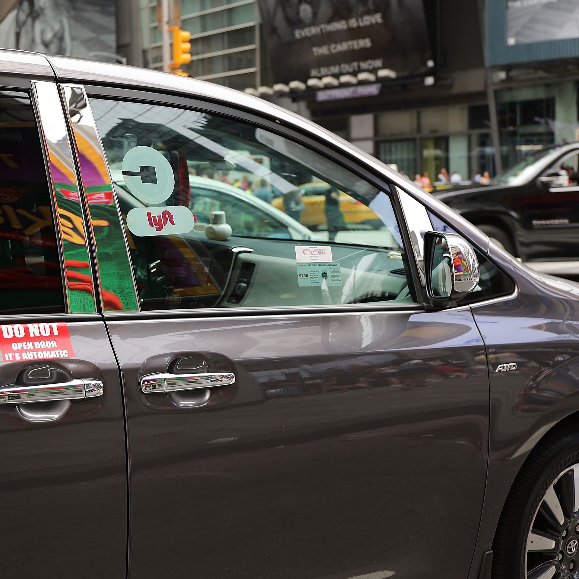 A van with Lyft and Uber window stickers moves through traffic in Manhattan