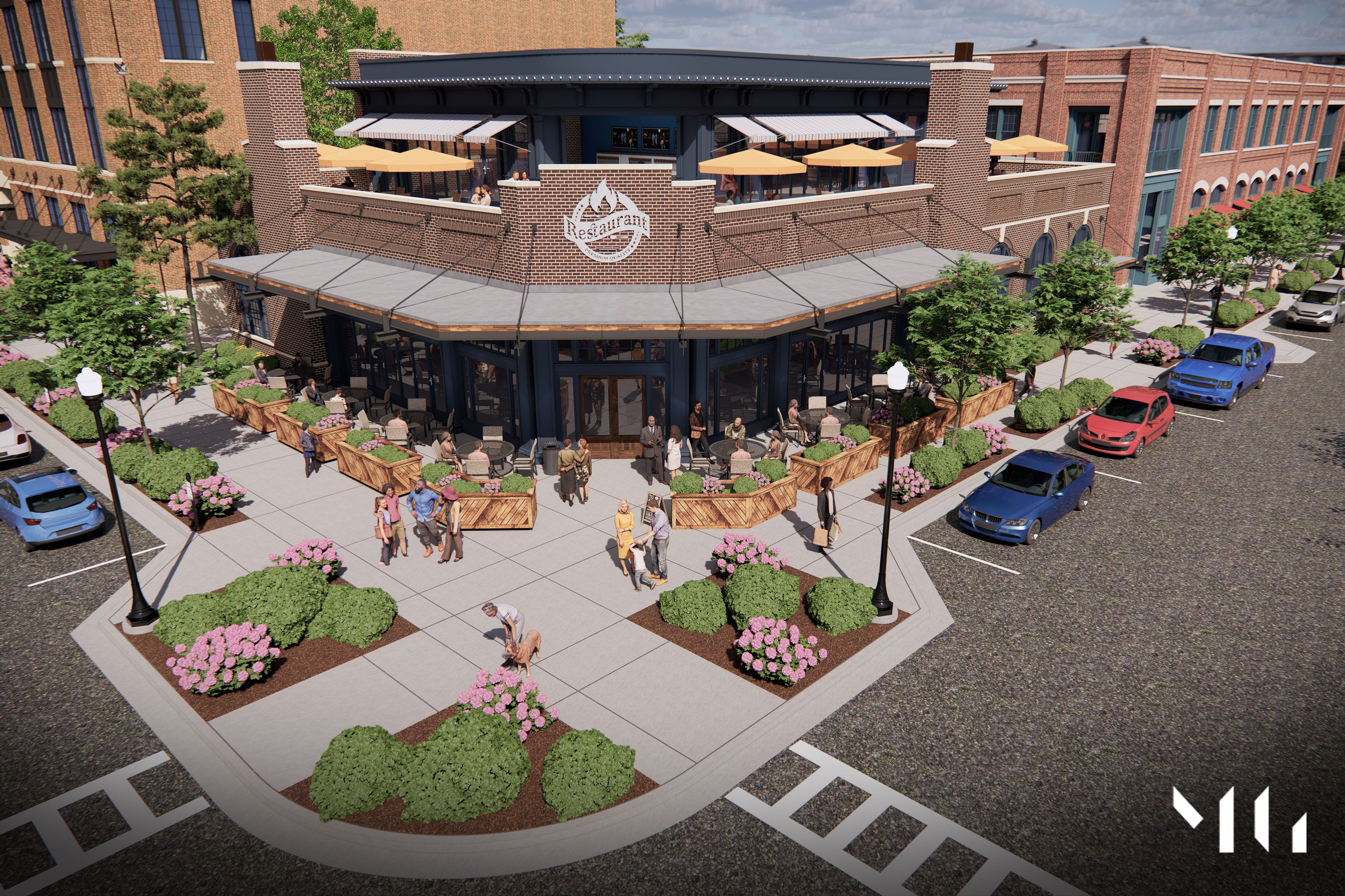 Street corner restaurant with brown brick exterior, outdoor seating on ground and upper patios with yellow umbrellas, people walking and sitting, landscaped greenery and pink flowers.