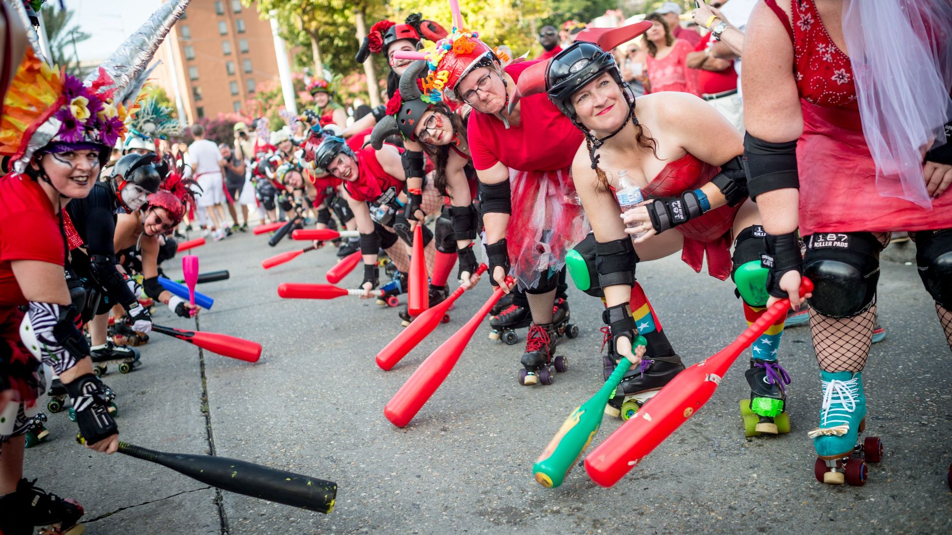 Photo shows roller derby girls forming a gauntlet with plastic bats for Running with the Bulls in New Orleans