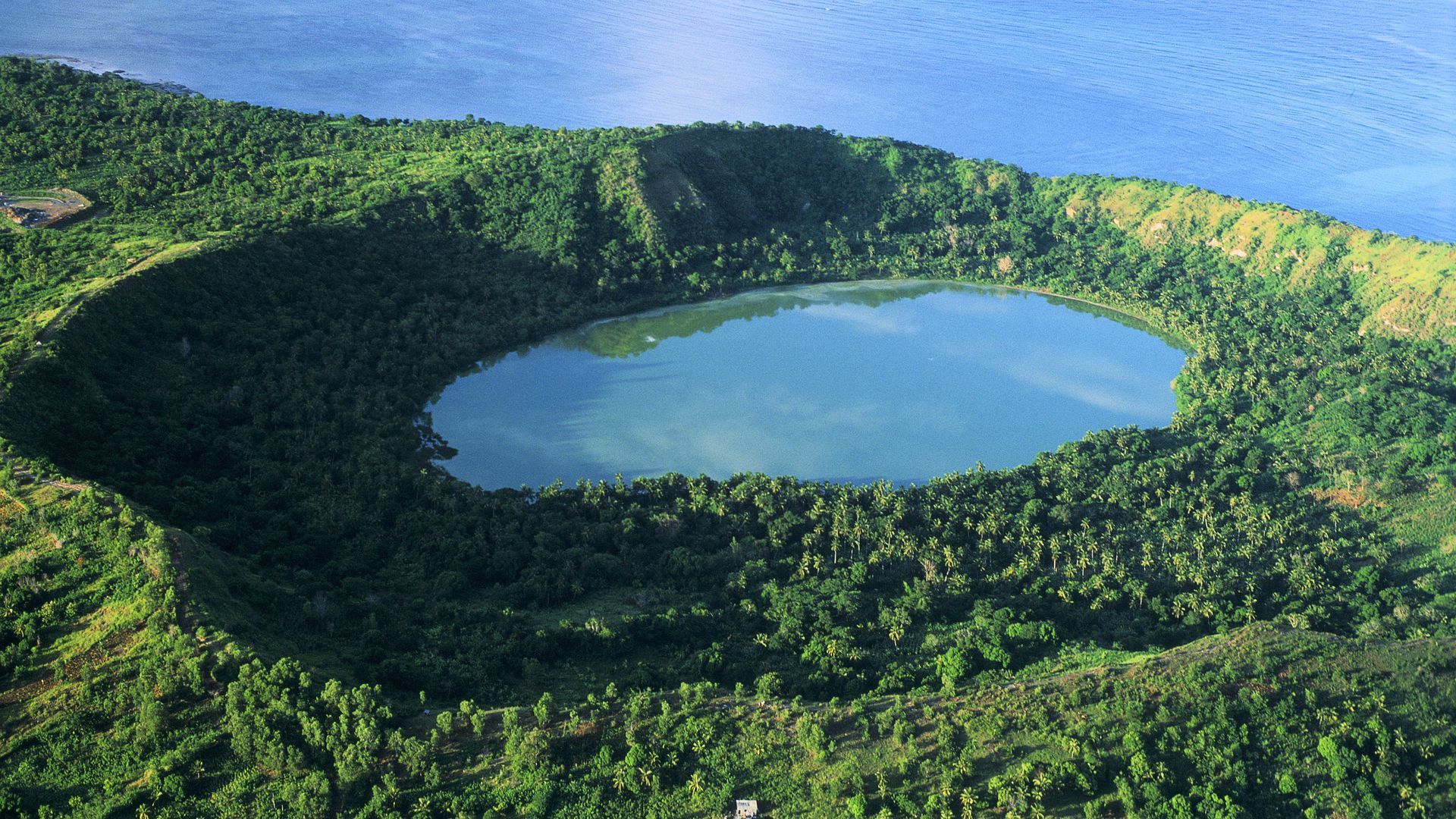 Photograph of a coastal crater lake surrounded by vegetation.