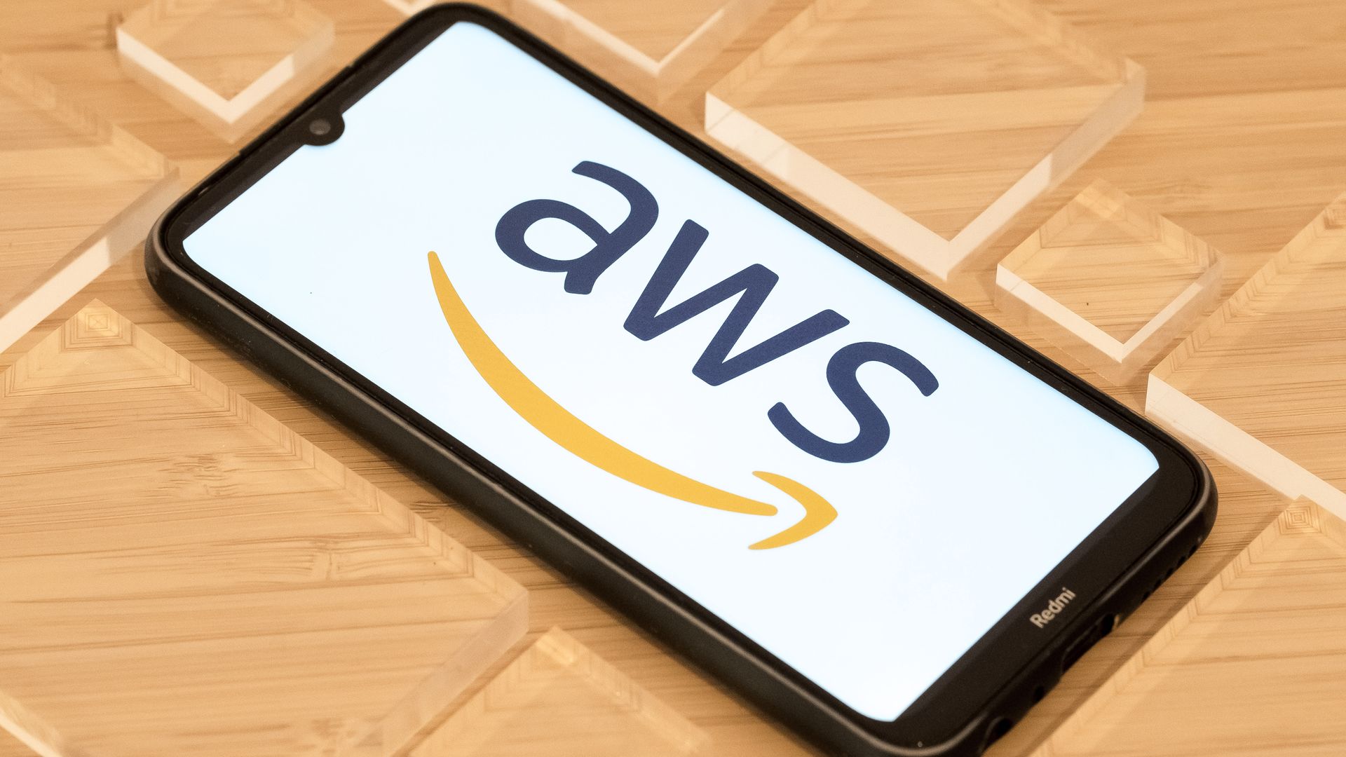 The logo for Amazon Web Services, which includes the letters "aws," is displayed on a smartphone.